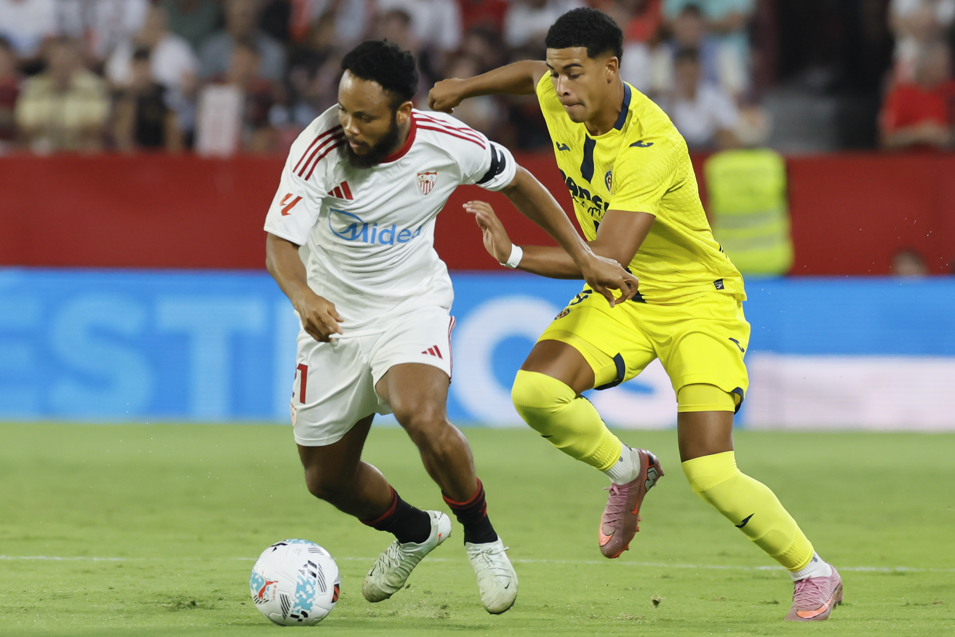 SEVILLA, 23/09/2025.- El delantero nigeriano del Sevilla Chidera Ejuke (i) se escapa del uruguayo Alvaro Mouriño, del Villarreal, durante el partido de la sexta jornada de LaLiga que Sevilla FC y Villarreal CF disputan hoy martes en el estadio Sánchez-Pizjuán, en Sevilla. EFE/José Manuel Vidal
