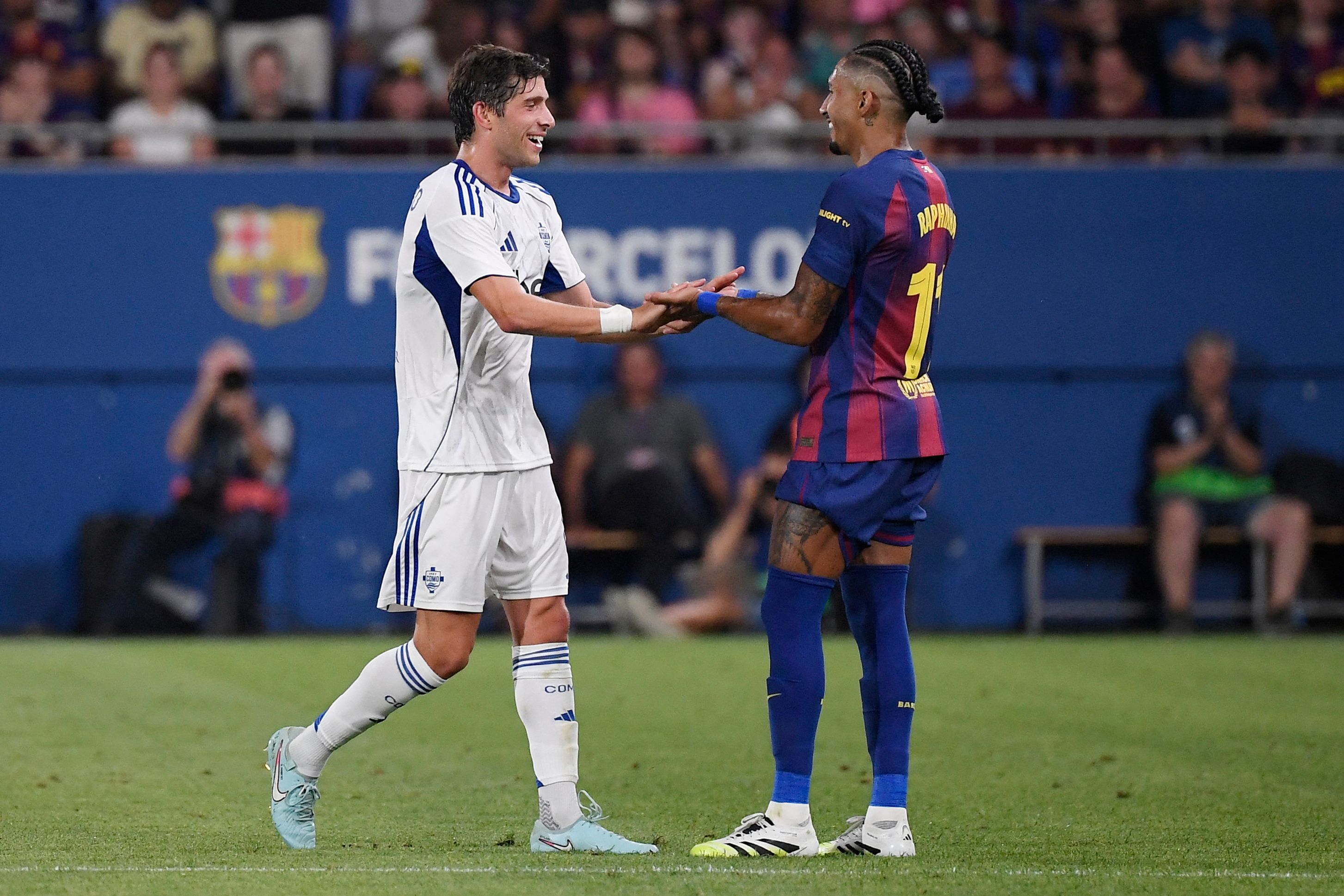Como's Spanish midfielder #08 Sergi Roberto (L) slaps hands with former teammate Barcelona's Brazilian forward #11 Raphinha during the 60th Joan Gamper Trophy football match between FC Barcelona and Como 1907 at Johan Cruyff Stadium in Barcelona on August 10, 2025. (Photo by Josep LAGO / AFP)