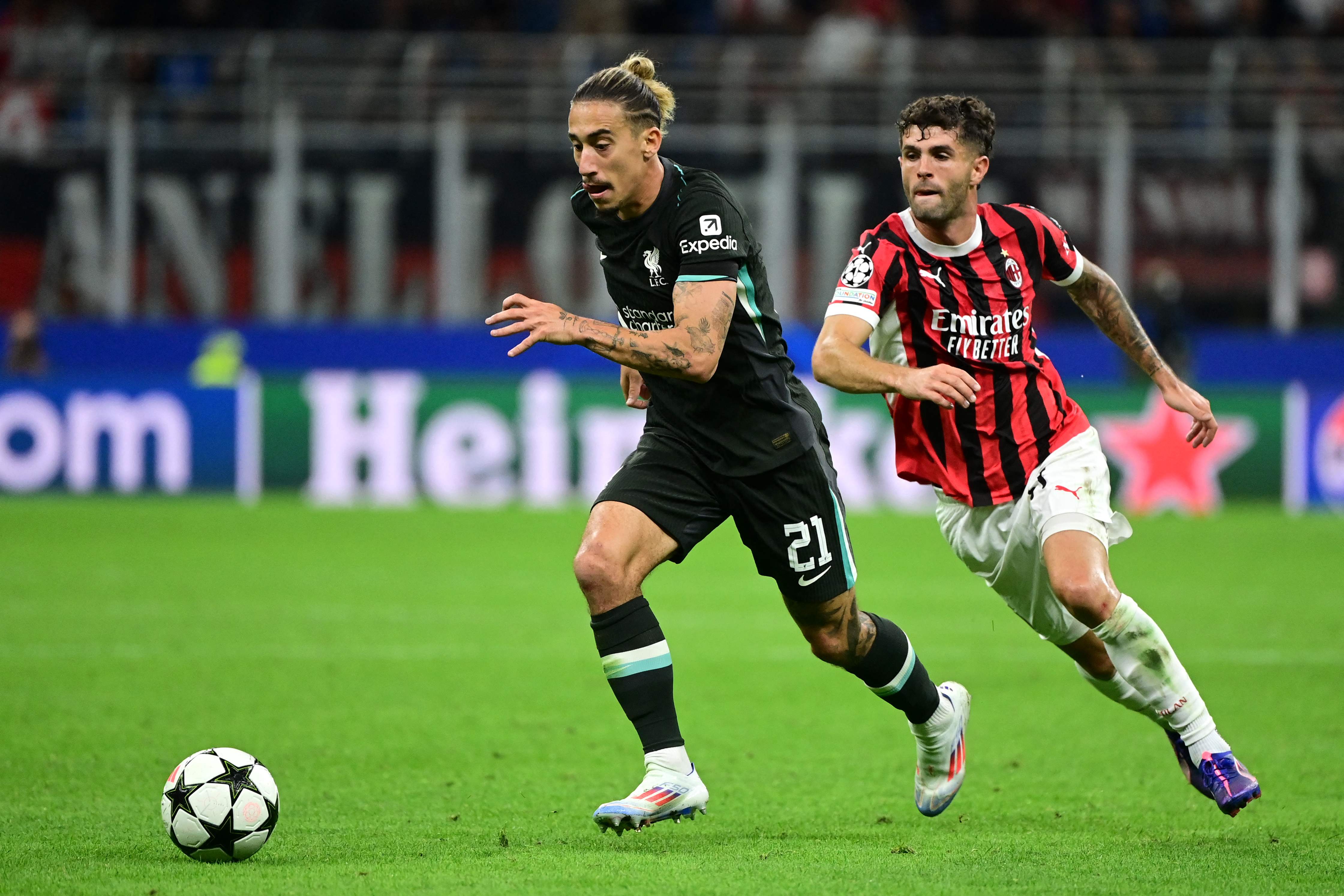 Liverpool's Greek defender #21 Kostas Tsimikas runs with the ball chased by AC Milan's US forward #11 Christian Pulisic during the UEFA Champions League 1st round day 1 football match between AC Milan and Liverpool FC at the San Siro stadium in Milan on September 17, 2024. (Photo by PIERO CRUCIATTI / AFP)