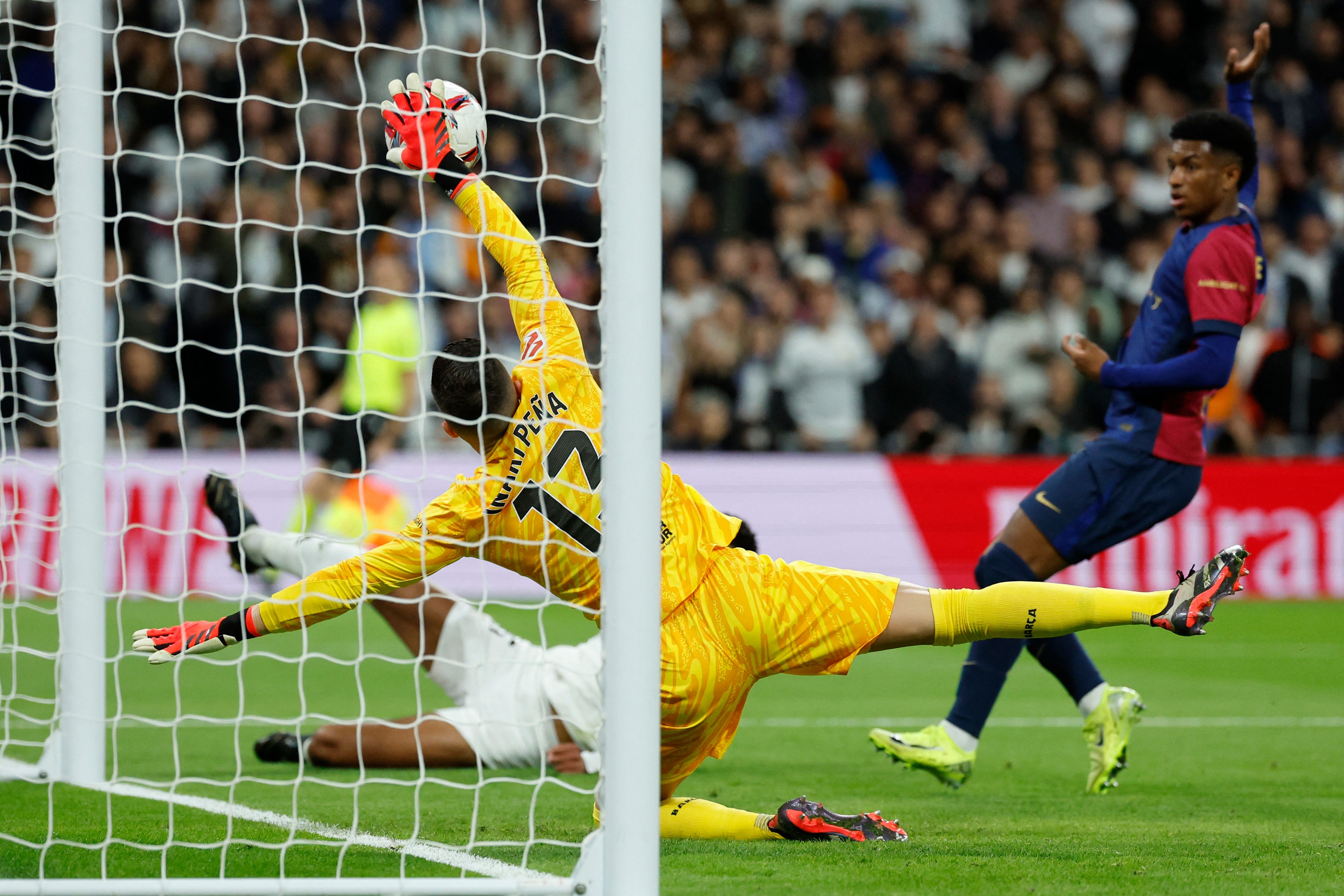 Barcelona's Spanish goalkeeper #13 Inaki Pena saves an attempt on goal by Real Madrid's English midfielder #05 Jude Bellingham during the Spanish league football match between Real Madrid CF and FC Barcelona at the Santiago Bernabeu stadium in Madrid on October 26, 2024. (Photo by OSCAR DEL POZO / AFP)