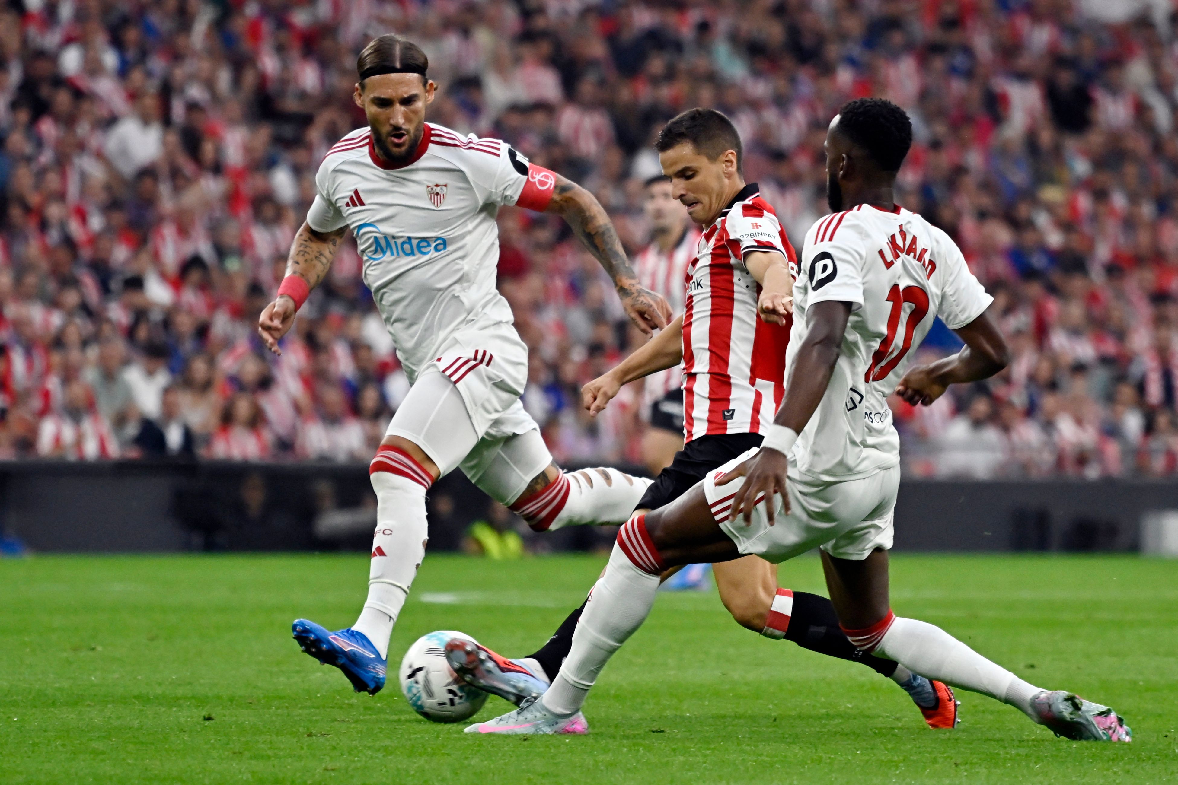 Sevilla's Serbian midfielder #06 Nemanja Gudelj (L), Athletic Bilbao's Spanish midfielder #16 Inigo Ruiz de Galarreta and Sevilla's Belgian forward #10 Dodi Lukebakio fight for the ball during the Spanish league football match between Athletic Club Bilbao and Sevilla FC at San Mames Stadium in Bilbao on August 17, 2025. (Photo by ANDER GILLENEA / AFP)