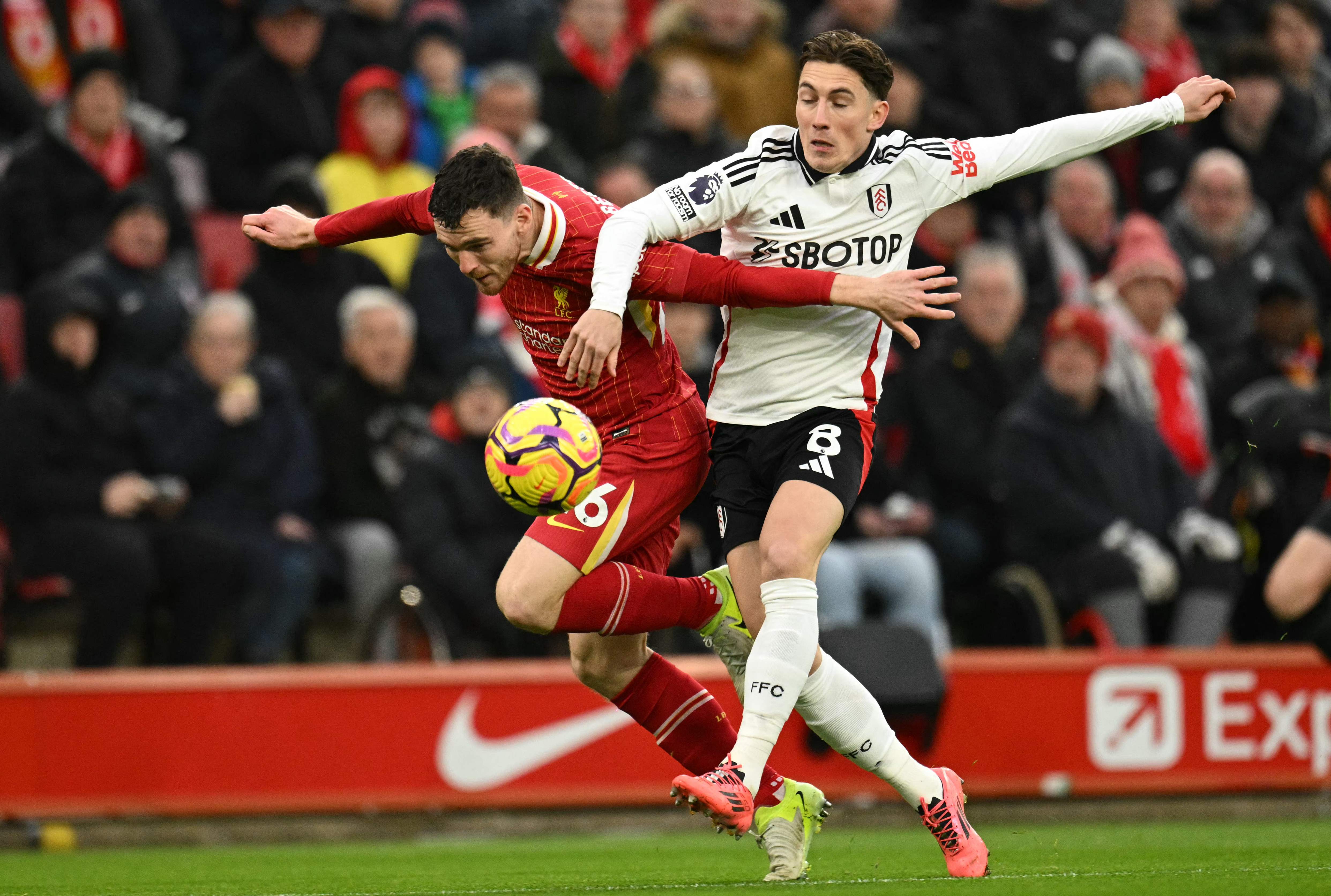 Liverpool's Scottish defender #26 Andrew Robertson (L) vies with Fulham's Welsh midfielder #08 Harry Wilson (C) during the English Premier League football match between Liverpool and Fulham at Anfield in Liverpool, north west England on December 14, 2024. (Photo by Oli SCARFF / AFP) / RESTRICTED TO EDITORIAL USE. No use with unauthorized audio, video, data, fixture lists, club/league logos or 'live' services. Online in-match use limited to 120 images. An additional 40 images may be used in extra time. No video emulation. Social media in-match use limited to 120 images. An additional 40 images may be used in extra time. No use in betting publications, games or single club/league/player publications. /