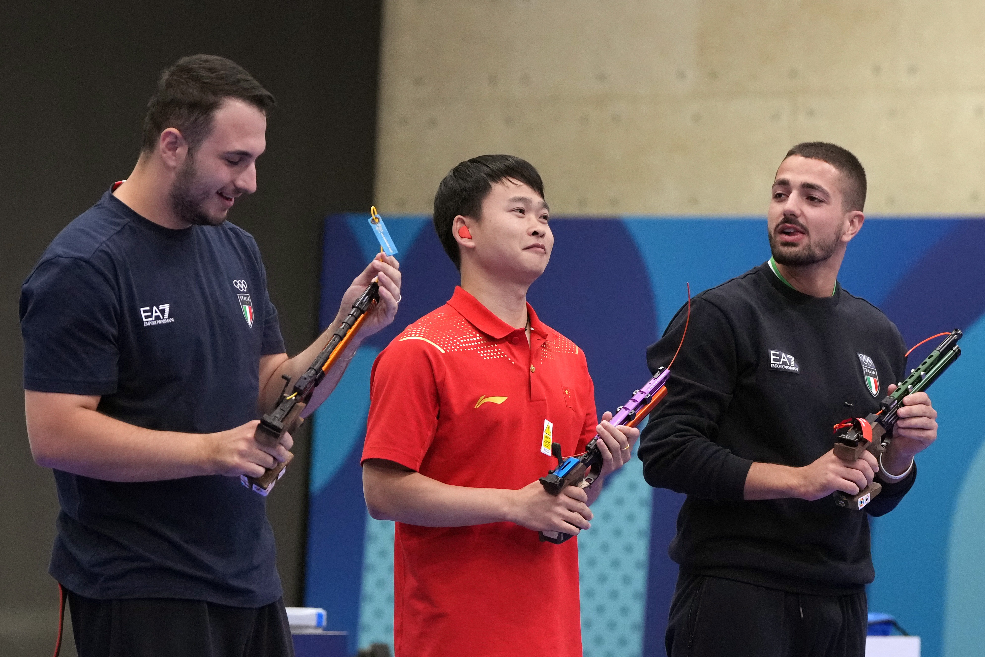 PARIS 2024 OLYMPICS  - Shooting - 10m Air Pistol Men's Final - Chateauroux Shooting Centre, Dols, France - July 28, 2024. (L-R) Federico Nilo Maldini of Italy  , Yu Xie (C) of China, and Paolo Monna of Italy pose with their pistols after finishing second, first and third. REUTERS/Amr Alfiky