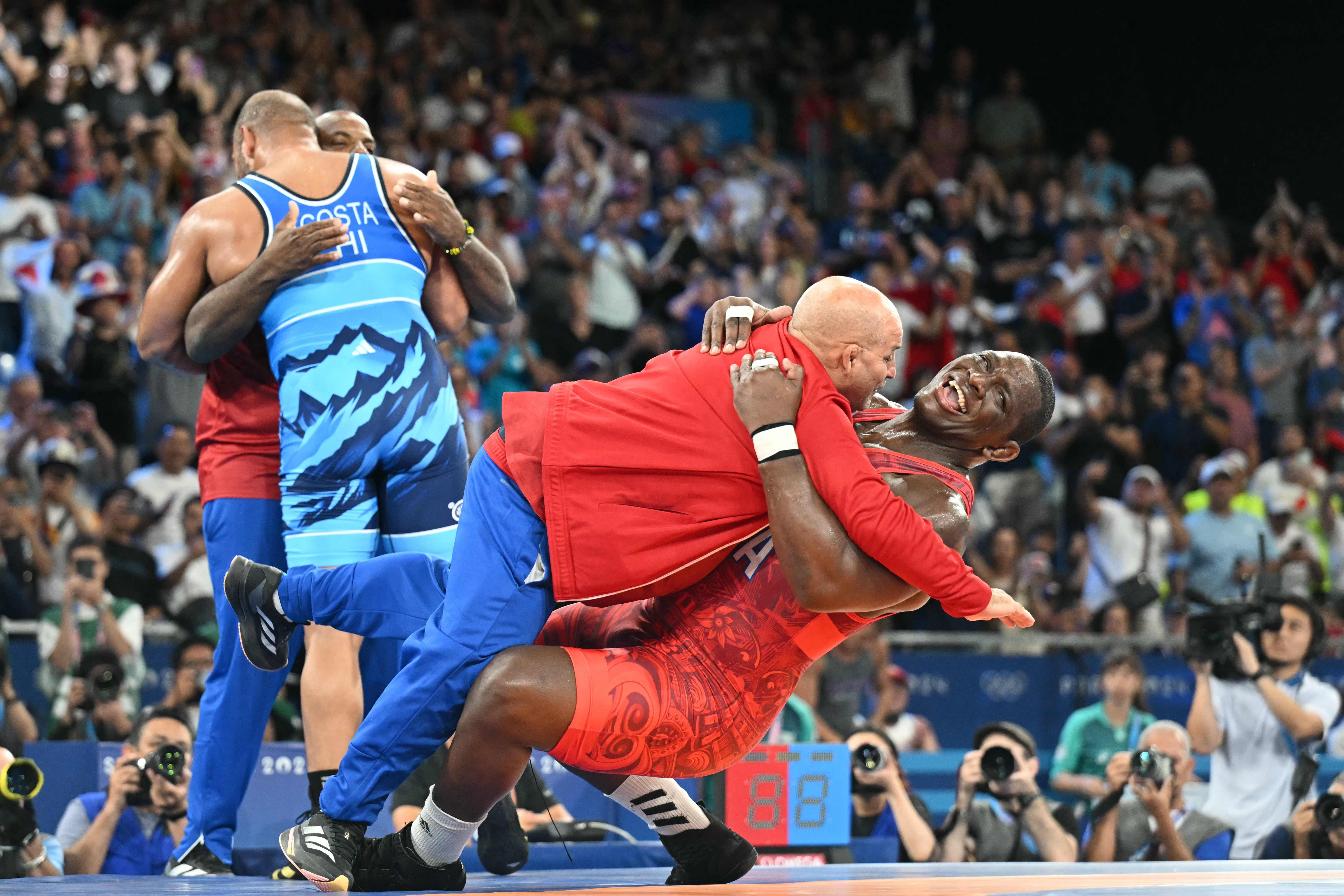 Cuba's Mijain Lopez Nunez celebrates with his coach after beating Chile's Yasmani Acosta Fernandez in their men's greco-roman 130kg wrestling final match at the Champ-de-Mars Arena during the Paris 2024 Olympic Games, in Paris on August 6, 2024. (Photo by Punit PARANJPE / AFP)