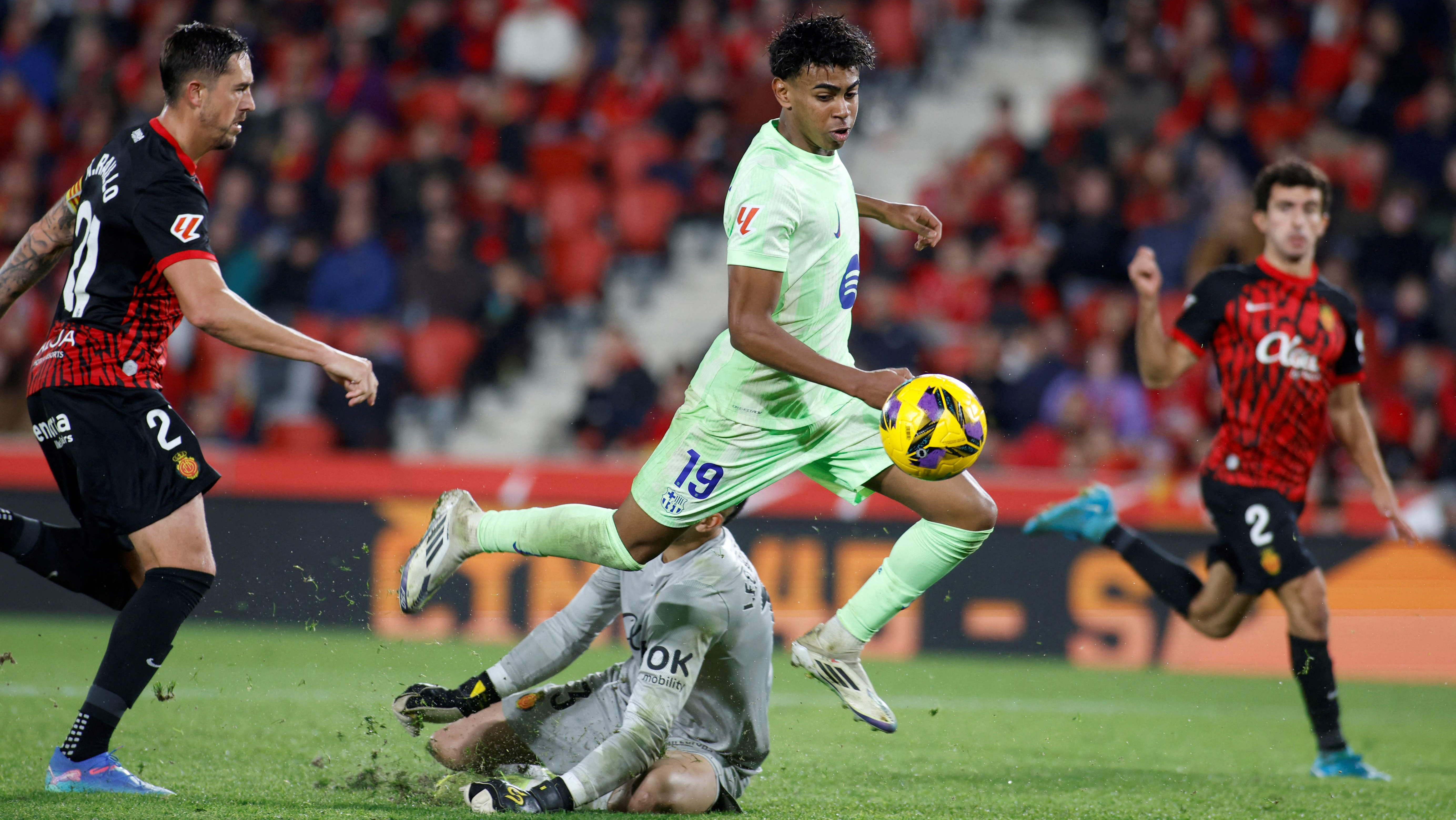 Barcelona's Spanish forward #19 Lamine Yamal challenges Real Mallorcas Spanish goalkeeper #13 Leo Roman during the Spanish league football match between RCD Mallorca and FC Barcelona at the Mallorca Son Moix stadium in Palma de Mallorca on December 3, 2024. (Photo by JAIME REINA / AFP)