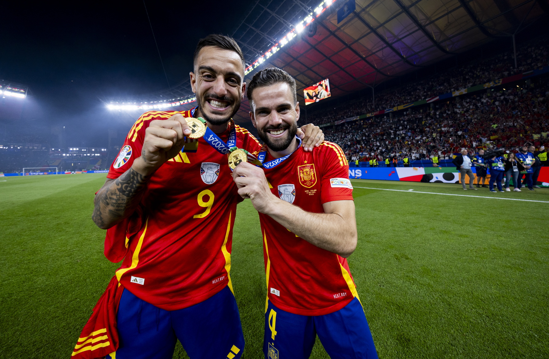 Joselu y Nacho Fernández, muestran sus medallas que les acreditan campeones de la Eurocopa.