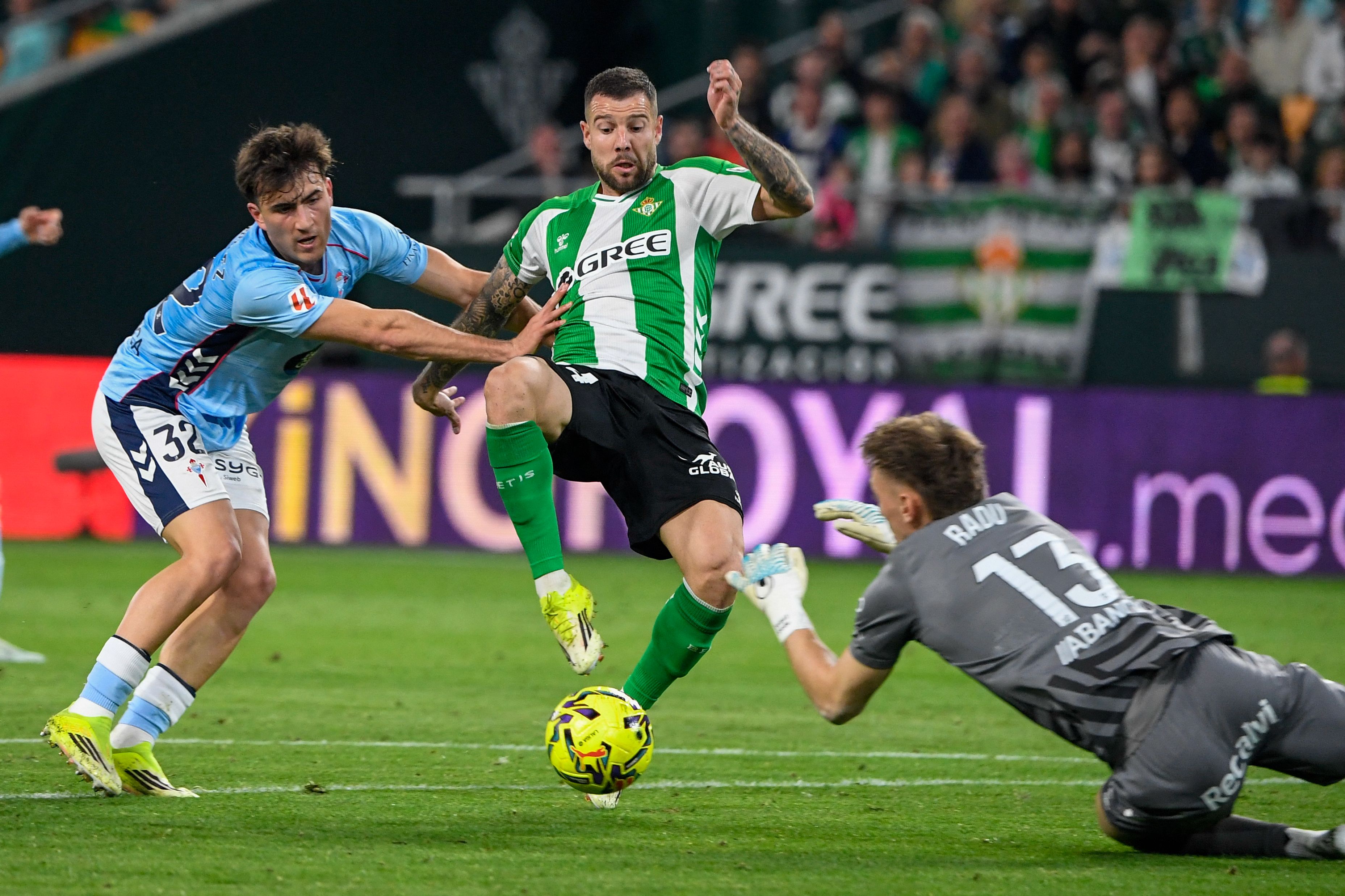 Real Betis' Spanish defender #24 Aitor Ruibal Garcia (C) is challenged for the ball by Celta Vigo's Romanian goalkeeper #13 Ionut Andrei Radu (R) and Celta Vigo's Spanish defender #32 Javier Rodriguez during the Spanish league football match between Real Betis and RC Celta de Vigo at Benito Villamarin Stadium in Seville on March 15, 2026. (Photo by CRISTINA QUICLER / AFP)