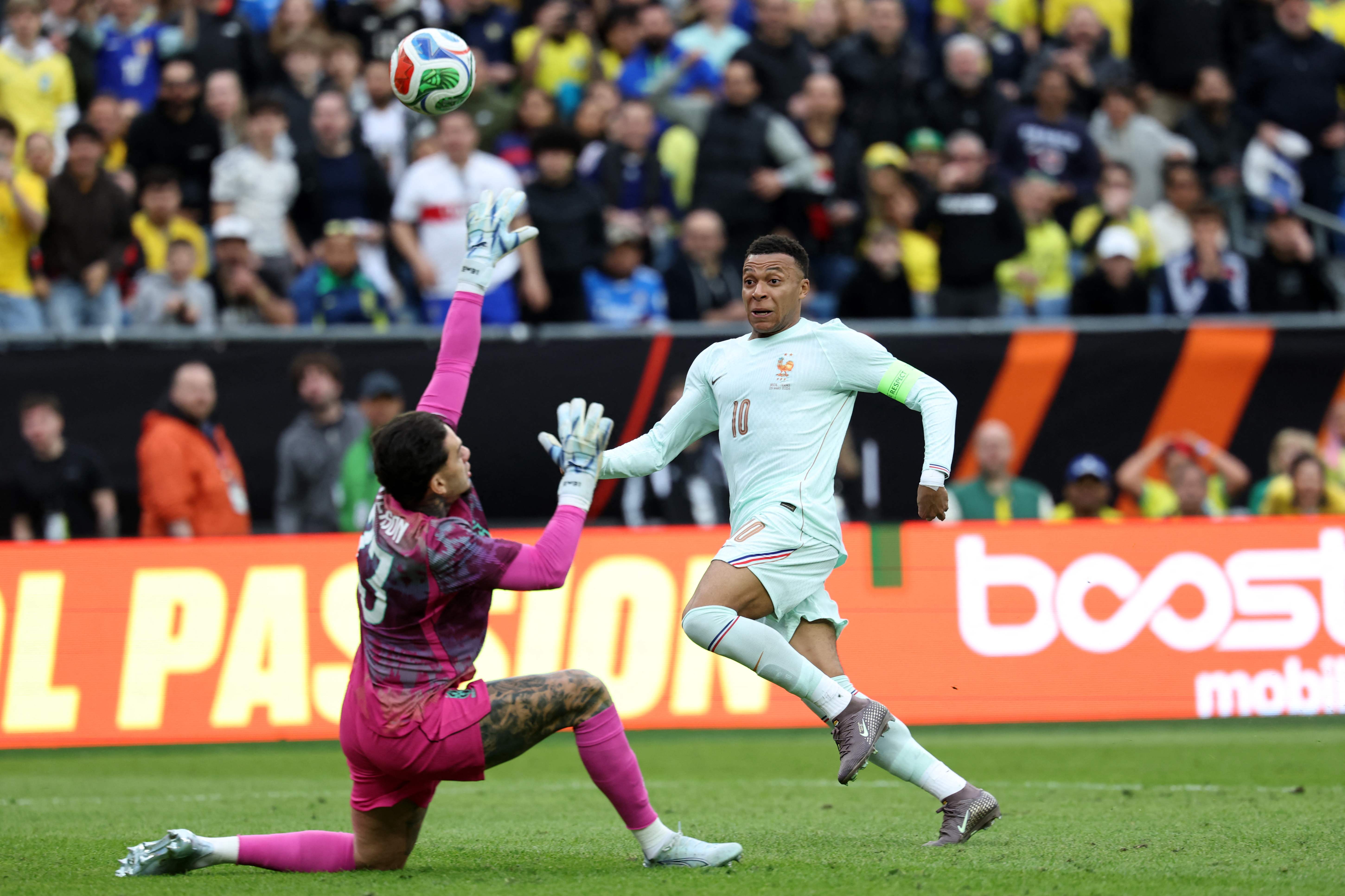 TOPSHOT - France's forward #10 Kylian Mbappe shoots above Brazil's goalkeeper #23 Ederson to score during a friendly football match between Brazil and France at Gillette Stadium in Foxborough, Massachusetts, on March 26, 2026. (Photo by FRANCK FIFE / AFP)