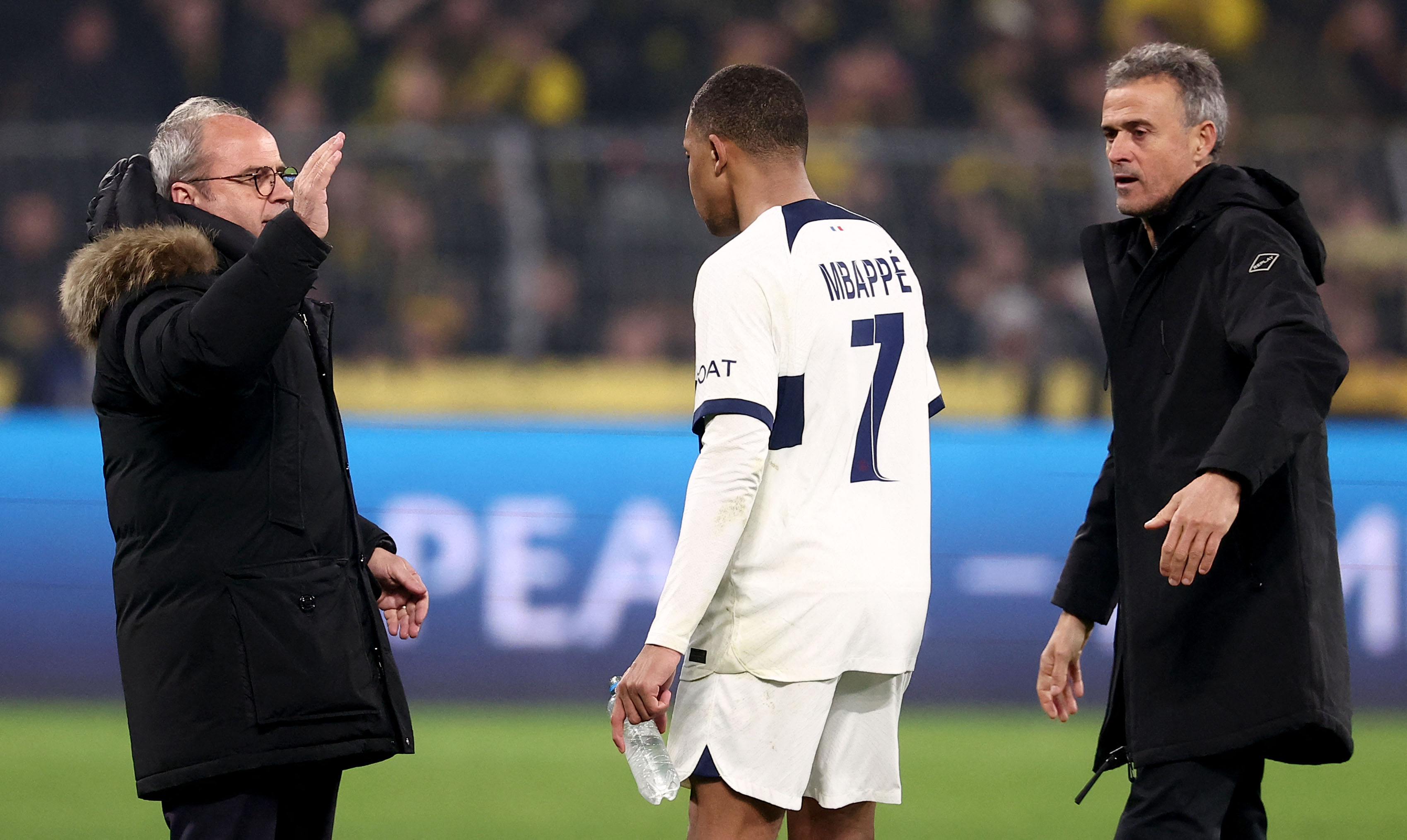 (L-R) Paris Saint Germain's Portuguese Football Advisor Luis Campos, Paris Saint-Germain's French forward #07 Kylian Mbappe and Paris Saint-Germain's Spanish headcoach Luis Enrique react after the UEFA Champions League group F football match between BVB Borussia Dortmund and Paris Saint-Germain in Dortmund, western Germany, on December 13, 2023. (Photo by FRANCK FIFE / AFP)