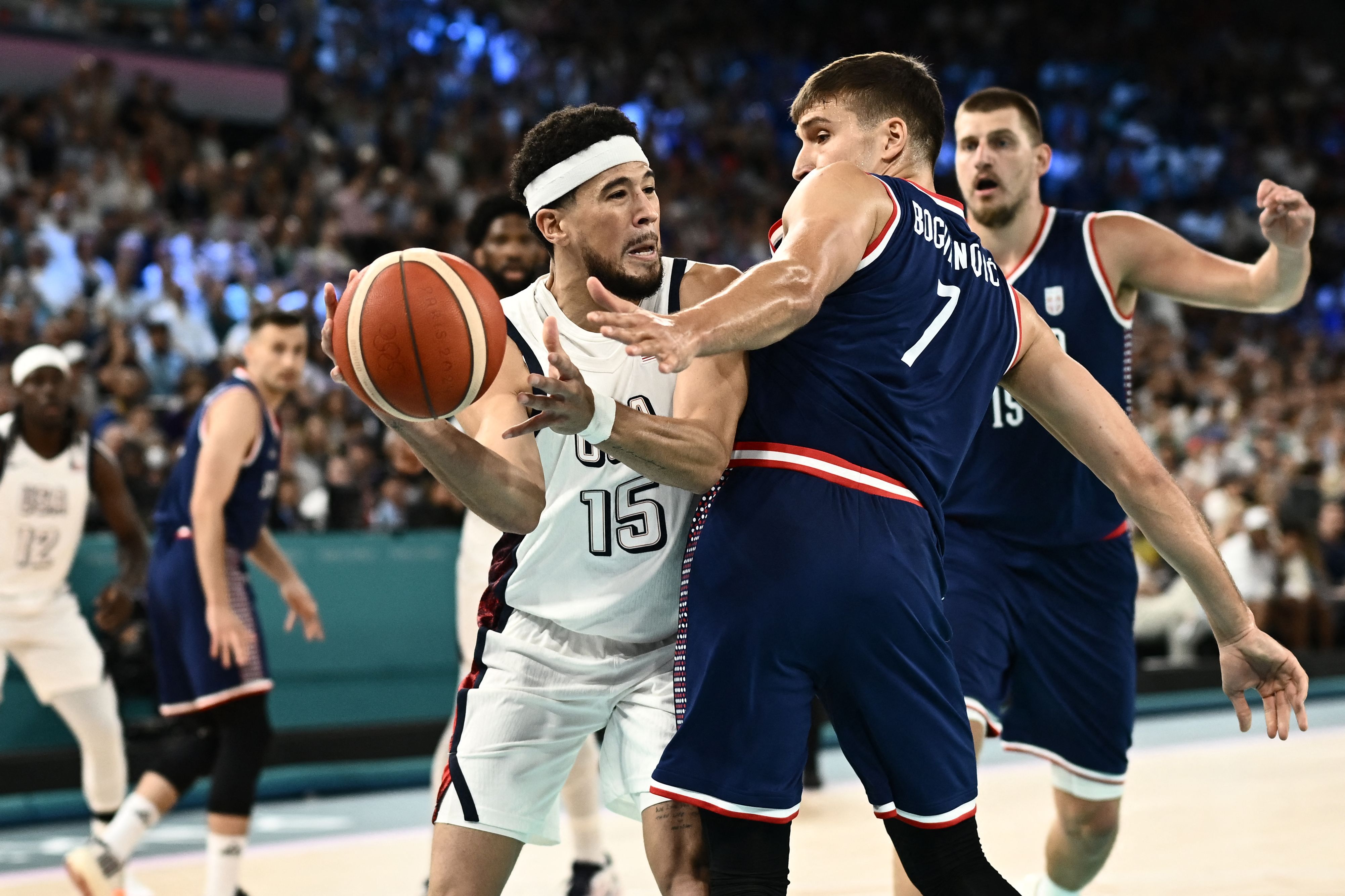 USA's #15 Devin Booker challenges Serbia's #07 Bogdan Bogdanovic (R) in the men's semifinal basketball match between USA and Serbia during the Paris 2024 Olympic Games at the Bercy  Arena in Paris on August 8, 2024. (Photo by Aris MESSINIS / AFP)