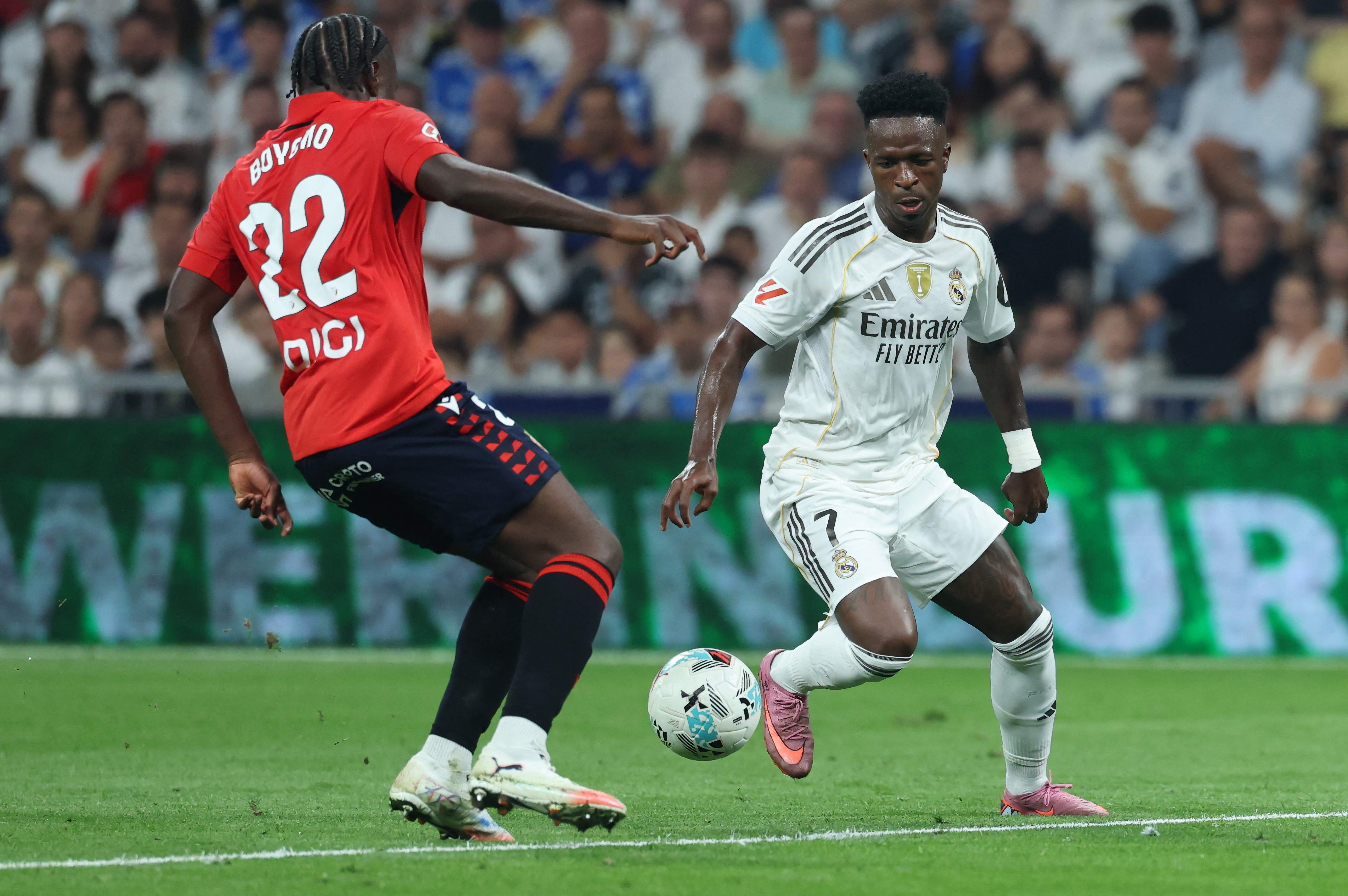 Osasuna's Cameroonian defender #22 Flavien Boyomo and Real Madrid's Brazilian forward #07 Vinicius Junior vie for the ball during the Spanish league football match between Real Madrid CF and CA Osasuna at Santiago Bernabeu Stadium in Madrid on August 19, 2025. (Photo by Thomas COEX / AFP)