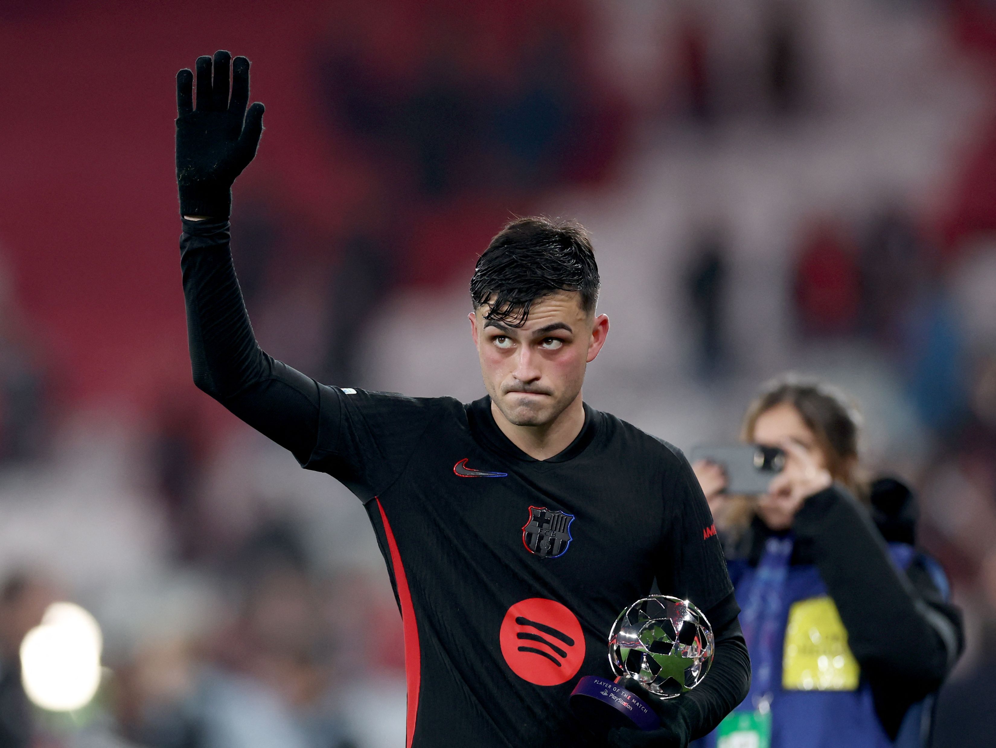 Barcelona's Spanish midfielder #08 Pedri salutes with this Player of the match Trophy at the end of the UEFA Champions League Round of 16 first leg football match between SL Benfica and FC Barcelona at Estadio da Luz stadium in Lisbon on March 5, 2025. Barcelona won 0-1. (Photo by FILIPE AMORIM / AFP)