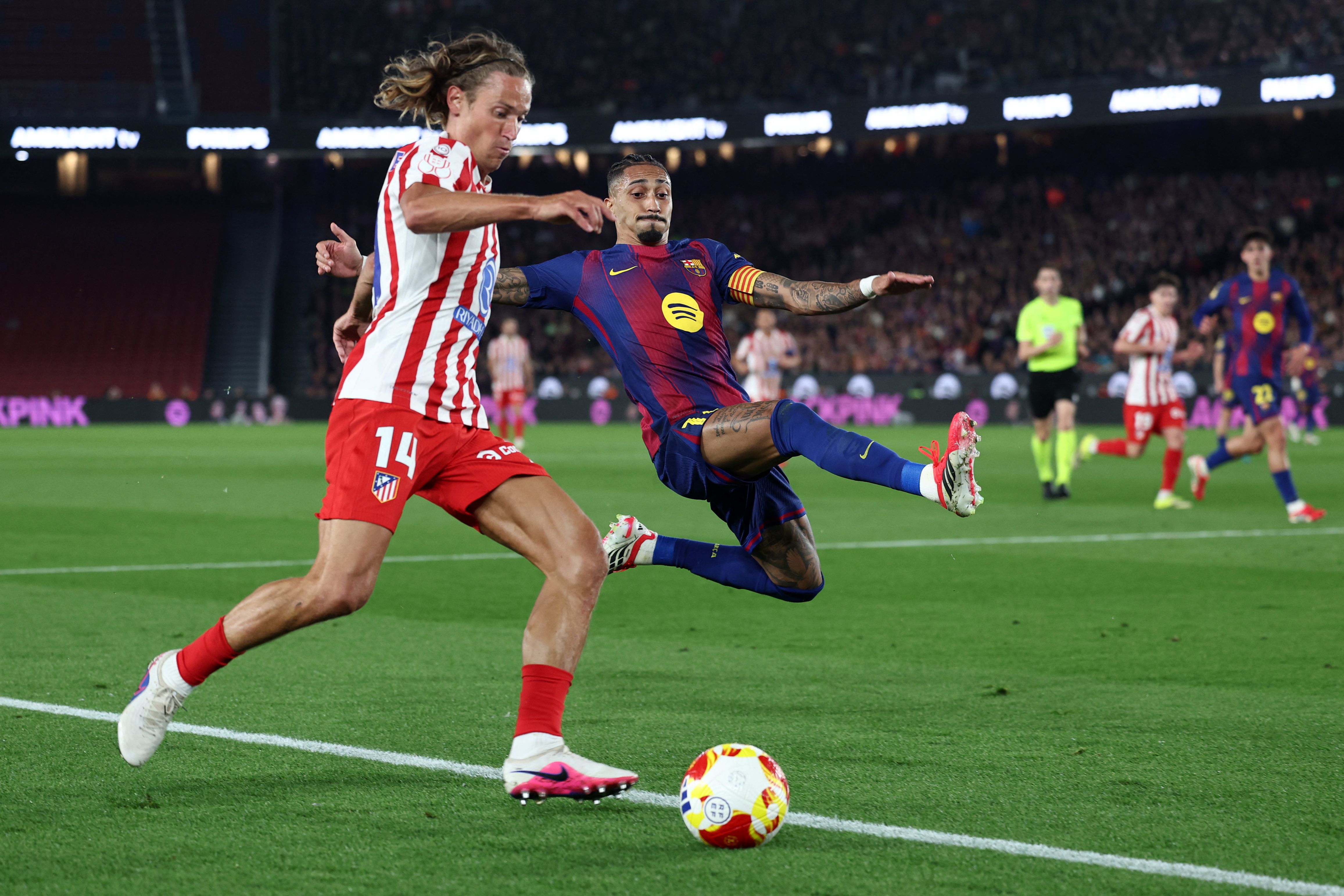 TOPSHOT - Barcelona's Brazilian forward #11 Raphinha (R) challenges Atletico Madrid's Spanish midfielder #14 Marcos Llorente during the Copa del Rey (King's Cup) semi final second leg football match between FC Barcelona and Club Atletico de Madrid at Camp Nou Stadium in Barcelona on March 3, 2026. (Photo by Josep LAGO / AFP)