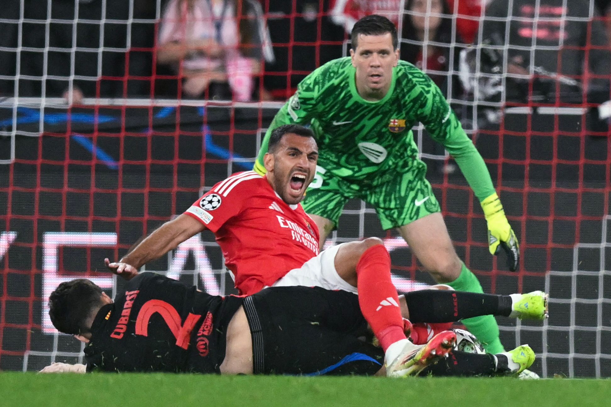 Benfica's Greek forward #14 Vangelis Pavlidis (top) tumbles with Barcelona's Spanish defender #02 Pau Cubarsi as Barcelona's Polish goalkeeper #25 Wojciech Szczesny watches during the UEFA Champions League Round of 16 first leg football match between SL Benfica and FC Barcelona at Estadio da Luz stadium in Lisbon on March 5, 2025. (Photo by Patricia DE MELO MOREIRA / AFP)