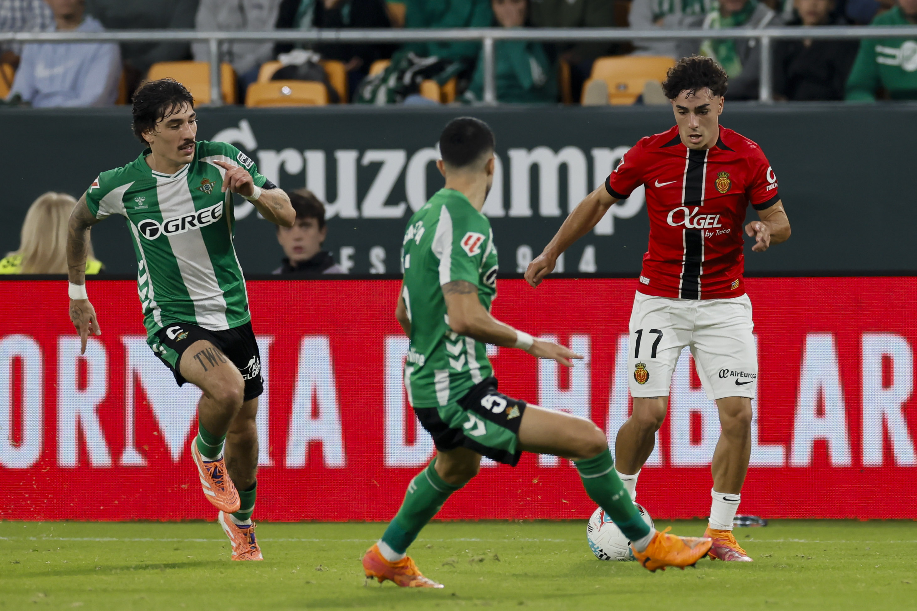 SEVILLA, 02/11/2025.- El centrocampista del Mallorca Jan Virgili (d) intenta superar a Marc Bartra (c), del Betis, durante el partido de la jornada 11 de LaLiga que Real Betis y RCD Mallorca disputan este domingo en el estadio de La Cartuja, en Sevilla. EFE/José Manuel Vidal
