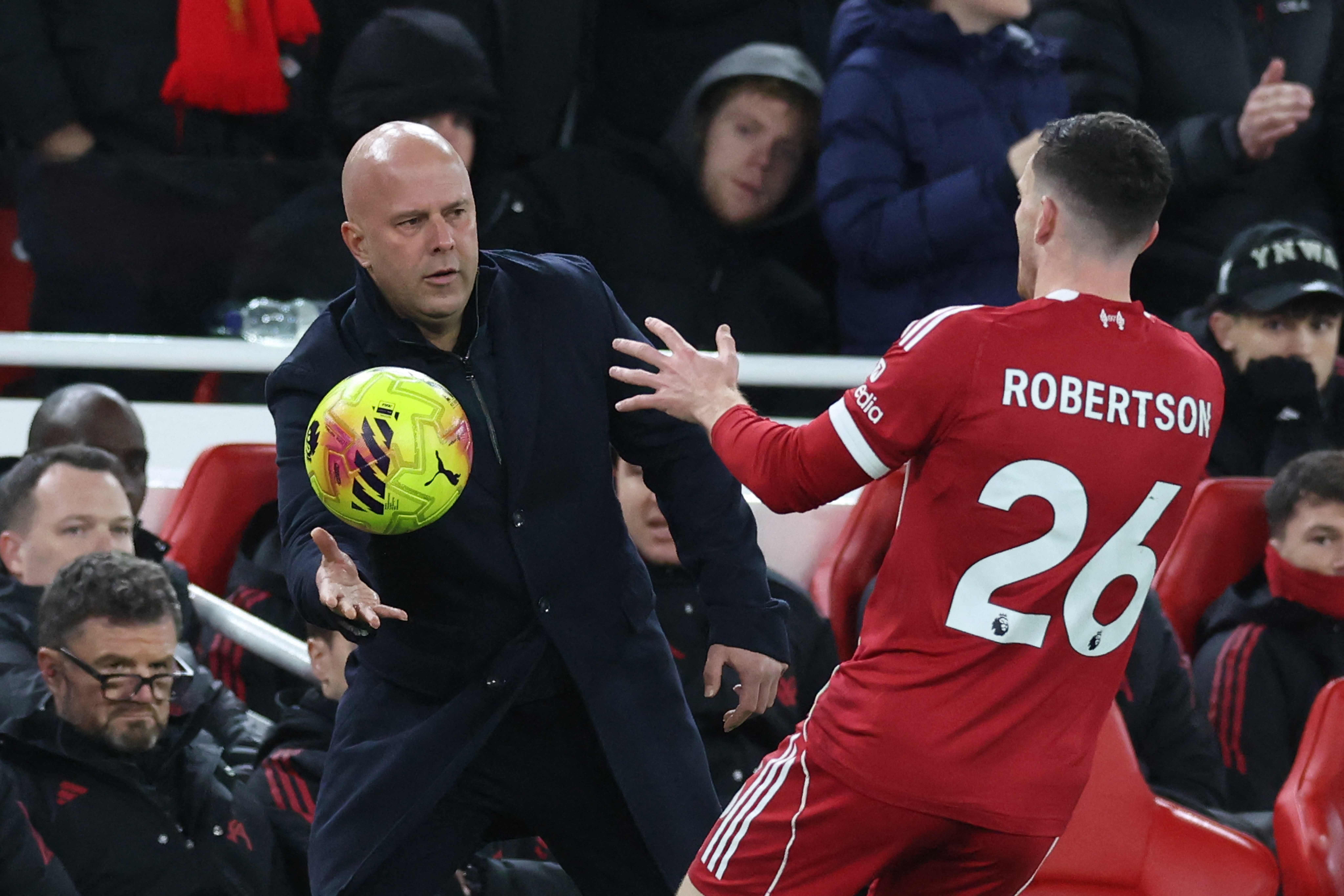 Liverpool's Dutch manager Arne Slot throws the ball to Liverpool's Scottish defender #26 Andrew Robertson during the English Premier League football match between Liverpool and Leeds United at Anfield in Liverpool, north west England on January 1, 2026. (Photo by Darren Staples / AFP) / RESTRICTED TO EDITORIAL USE. No use with unauthorized audio, video, data, fixture lists, club/league logos or 'live' services. Online in-match use limited to 120 images. An additional 40 images may be used in extra time. No video emulation. Social media in-match use limited to 120 images. An additional 40 images may be used in extra time. No use in betting publications, games or single club/league/player publications. / 