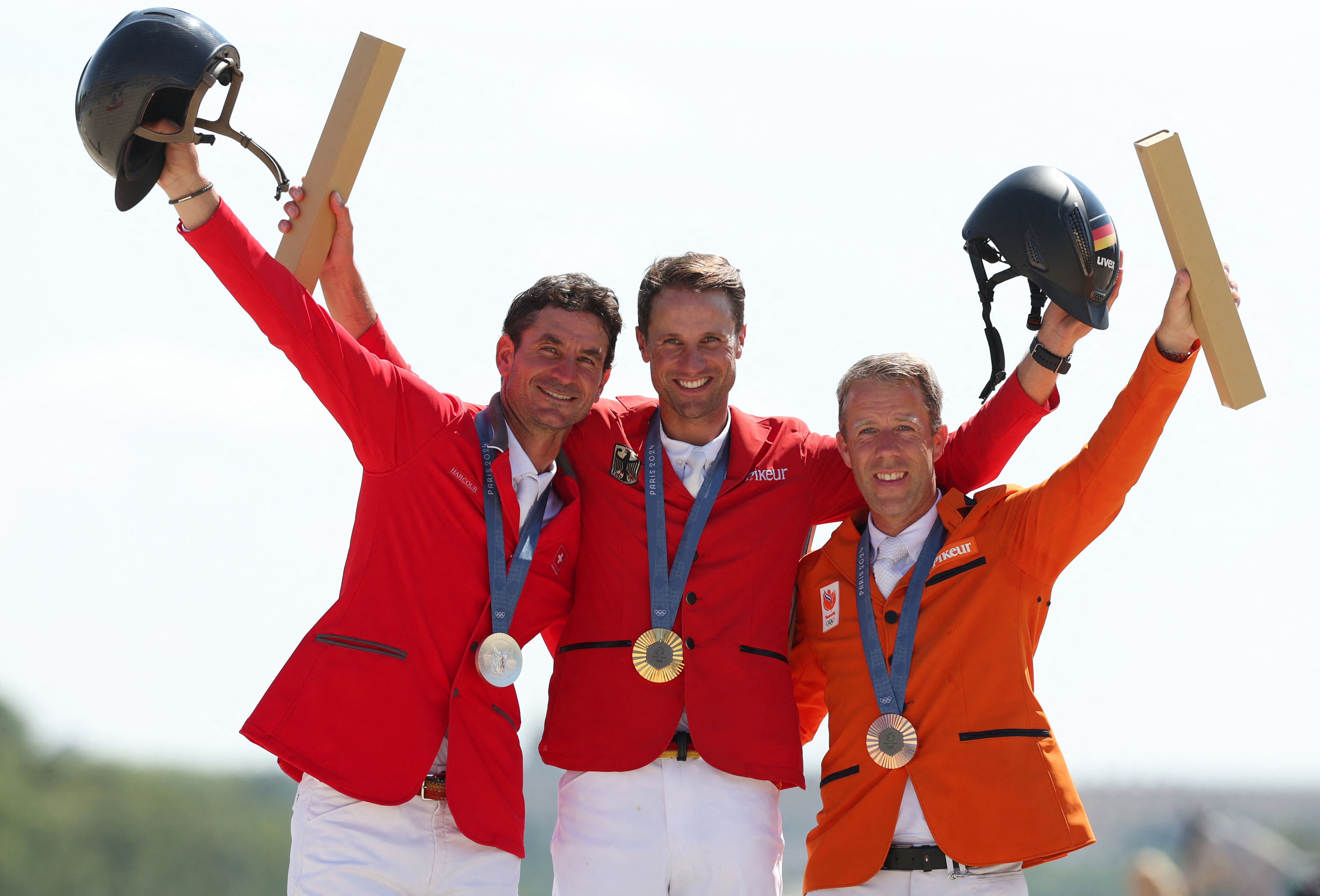 Silver medallist Switzerland's Steve Guerdat (L), gold medallist Germany's Christian Kukuk (C) and bronze medallist Netherlands' Maikel Van Der Vleuten (R) celebrate on the podium during the victory ceremony after the equestrian's jumping individual final during the Paris 2024 Olympic Games at the Chateau de Versailles, in Versailles, in the western outskirts of Paris, on August 6, 2024. (Photo by Pierre-Philippe MARCOU / AFP)