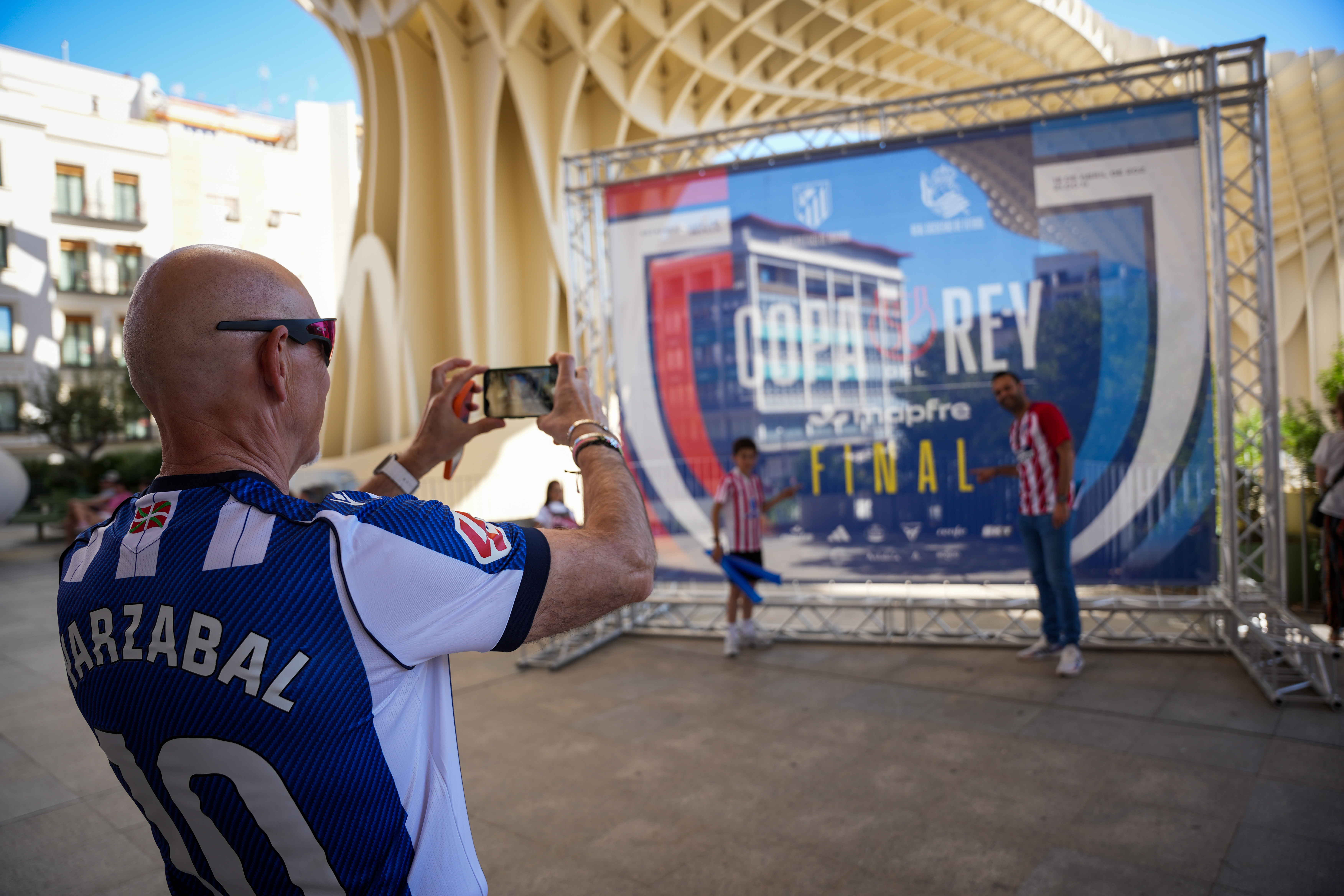 Un aficionado de la Real Sociedad le hace una foto a dos aficionados del Atlético de Madrid en Sevilla.