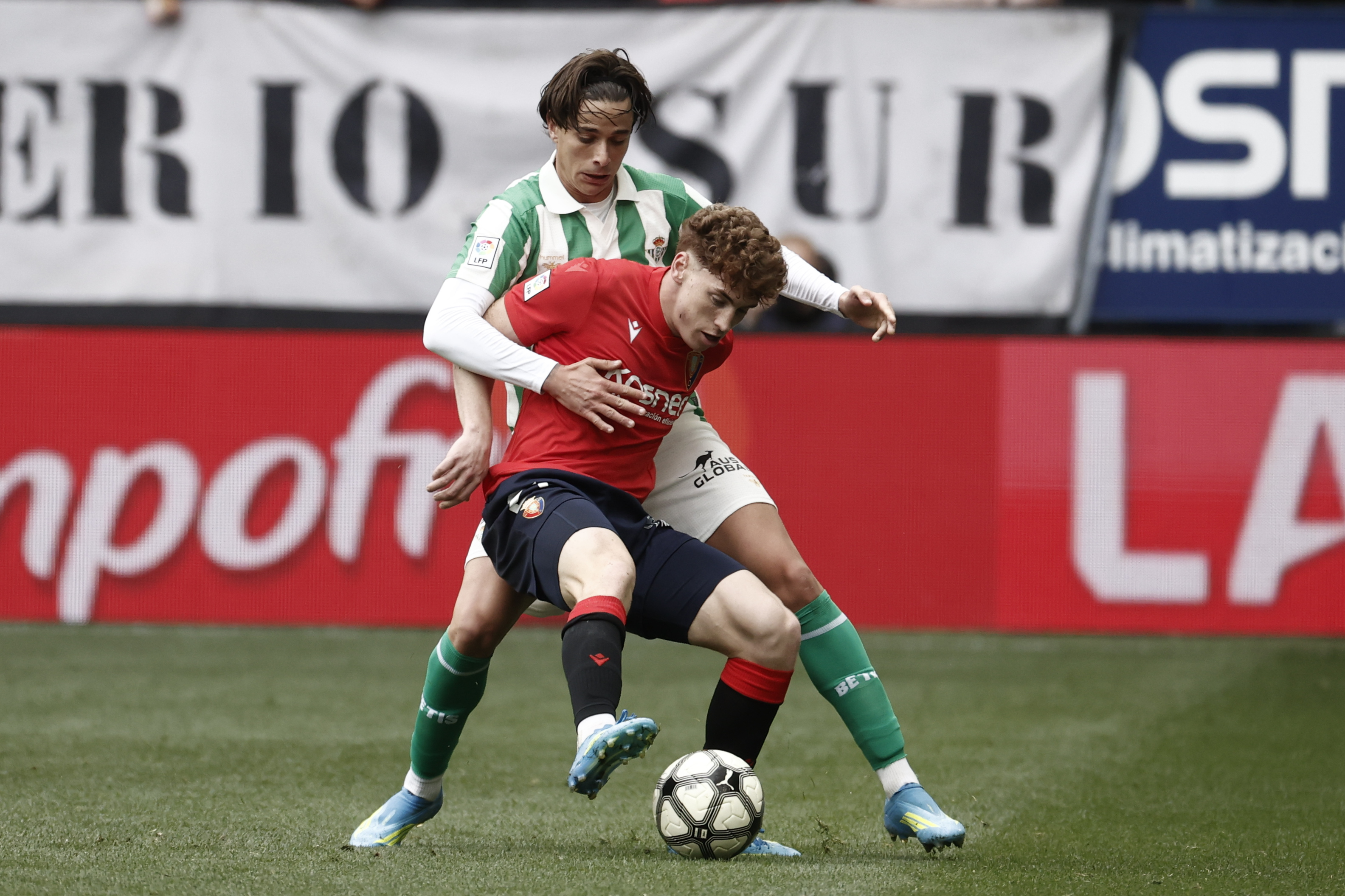PAMPLONA, 12/04/2026.- El delantero de Osasuna Víctor Muñoz (d) protege el balón ante el defensa del Osasuna Diego Gómez (i) durante el partido de Liga que Real Betis y Osasuna disputan este domingo en el estadio de El Sadar. EFE/Jesús Diges
