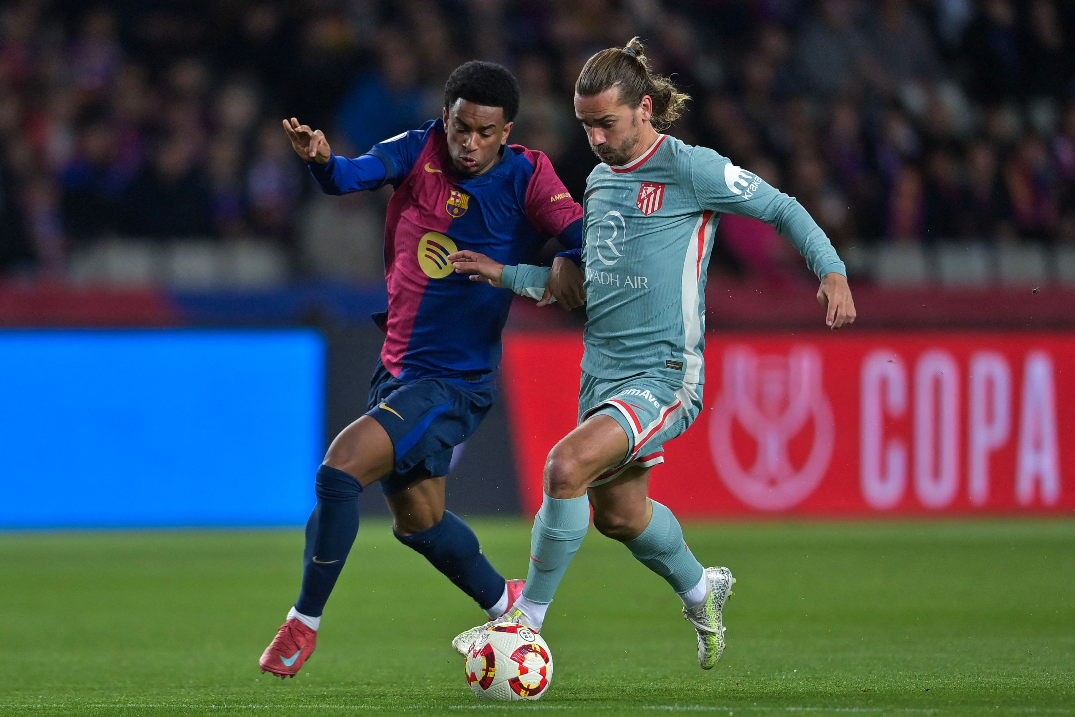 Atletico Madrid's French forward #07 Antoine Griezmann (R) is challenged by Barcelona's Spanish defender #03 Alex Balde before scoring their second goal during the Spanish Copa del Rey (King's Cup) semi-final first leg football match between FC Barcelona and Club Atletico de Madrid at at Estadi Olimpic Lluis Companys in Barcelona, on February 25, 2025. (Photo by MANAURE QUINTERO / AFP)