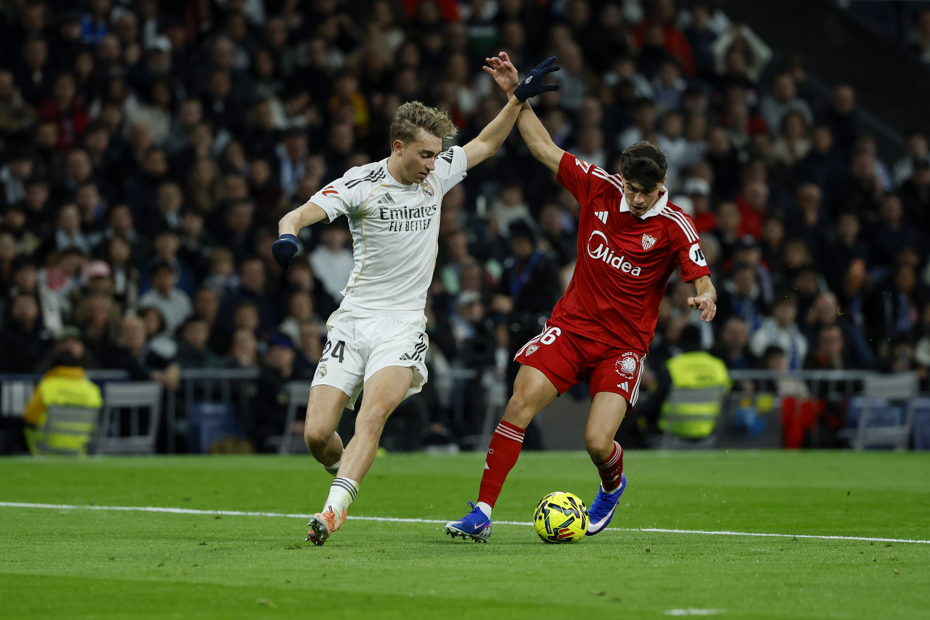 MADRID, 20/12/2025.- El defensa del Real Madrid, Dean Huijsen (i), disputa el balón ante el defensa del Sevilla, Juanlu Sánchez, durante el encuentro de la jornada 17 de LaLiga entre Real Madrid y Sevilla FC celebrado este sábado en el estadio Santiago Bernabéu, en Madrid. EFE / Juanjo Martín.
