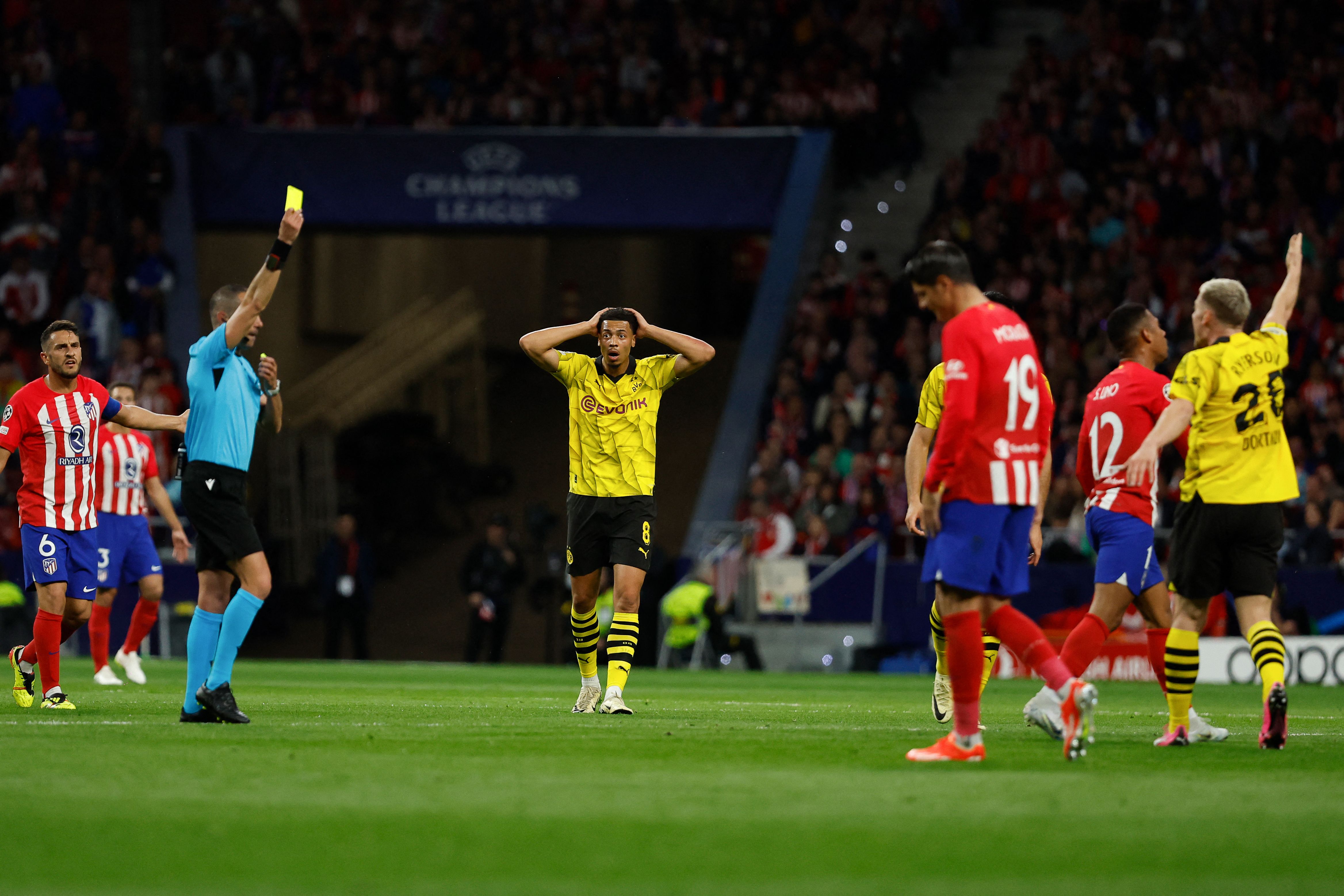 Italian referee Marco Guida shows a yellow card to Atletico Madrid's Brazilian forward #12 Samuel Lino during the UEFA Champions League quarter final first leg football match between Club Atletico de Madrid and Borussia Dortmund at the Metropolitano stadium in Madrid on April 10, 2024. (Photo by OSCAR DEL POZO / AFP)