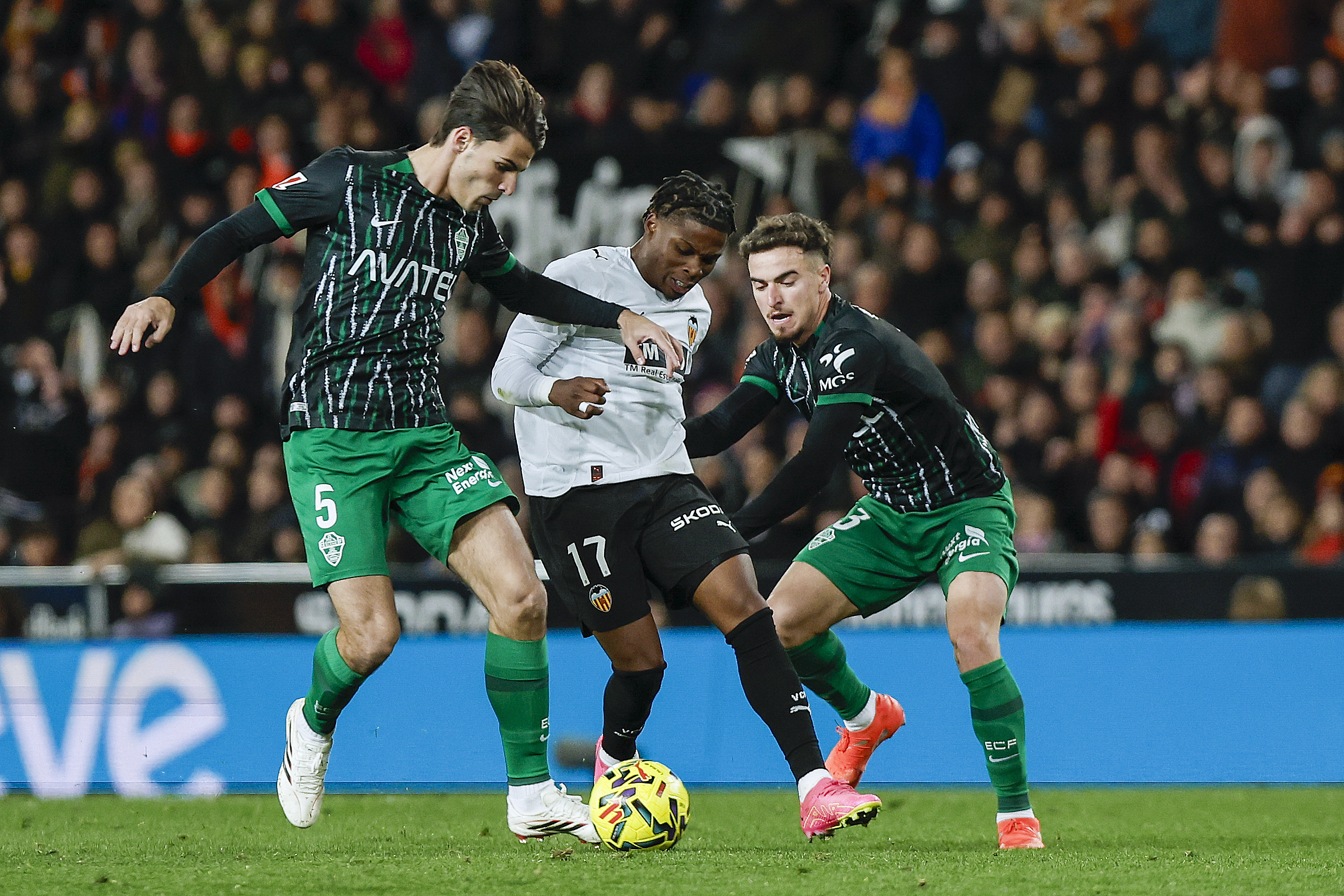 VALENCIA, 10/01/2026.- El delantero belga del Valencia, Largie Ramazani (c), disputa el balón ante los jugadores del Elche, Federico Redondo (i) y Victor Chust, durante el partido de la jornada 19 de LaLiga EA Sports que disputan el Valencia CFy el Elche CF este sábado, en el estadio de Mestalla. EFE/ Biel Aliño