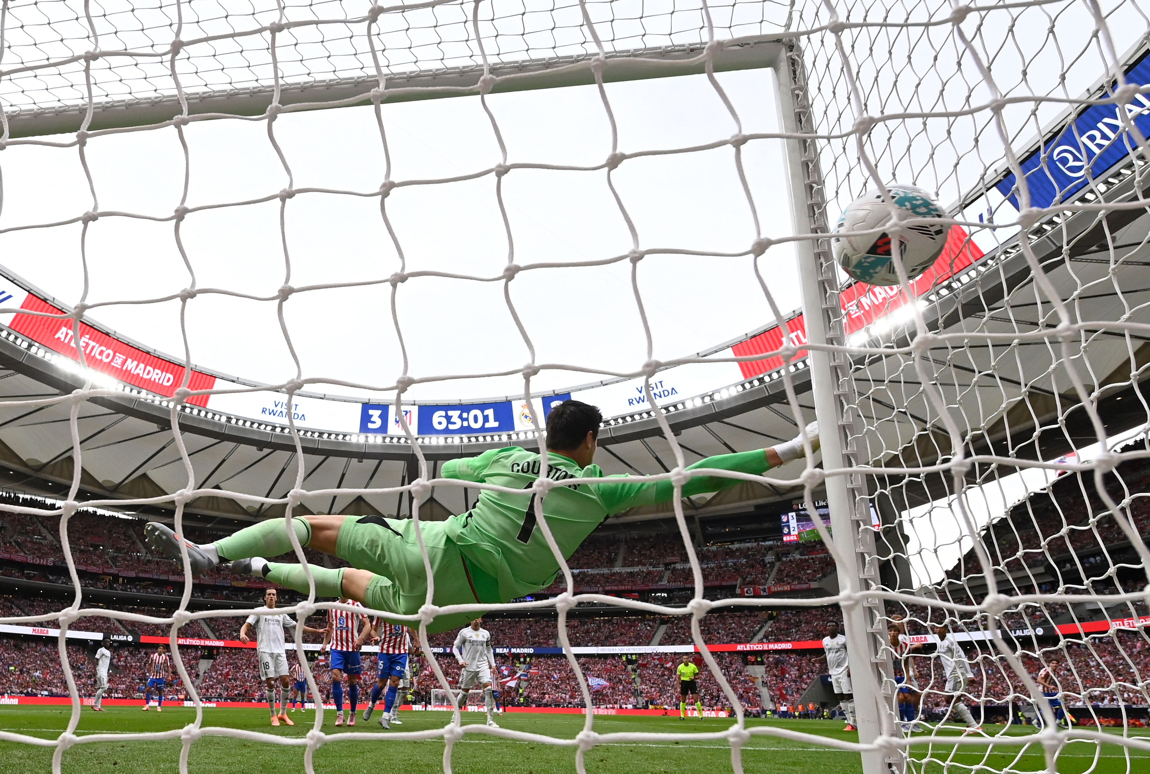 Atletico Madrid's Argentine forward #19 Julian Alvarez scores his team's third goal from the penalty spot in spite of Real Madrid's Belgian goalkeeper #01 Thibaut Courtois during the Spanish league football match between Club Atletico de Madrid and Real Madrid CF at the Metropolitano stadium in Madrid on September 27, 2025. (Photo by OSCAR DEL POZO / AFP)