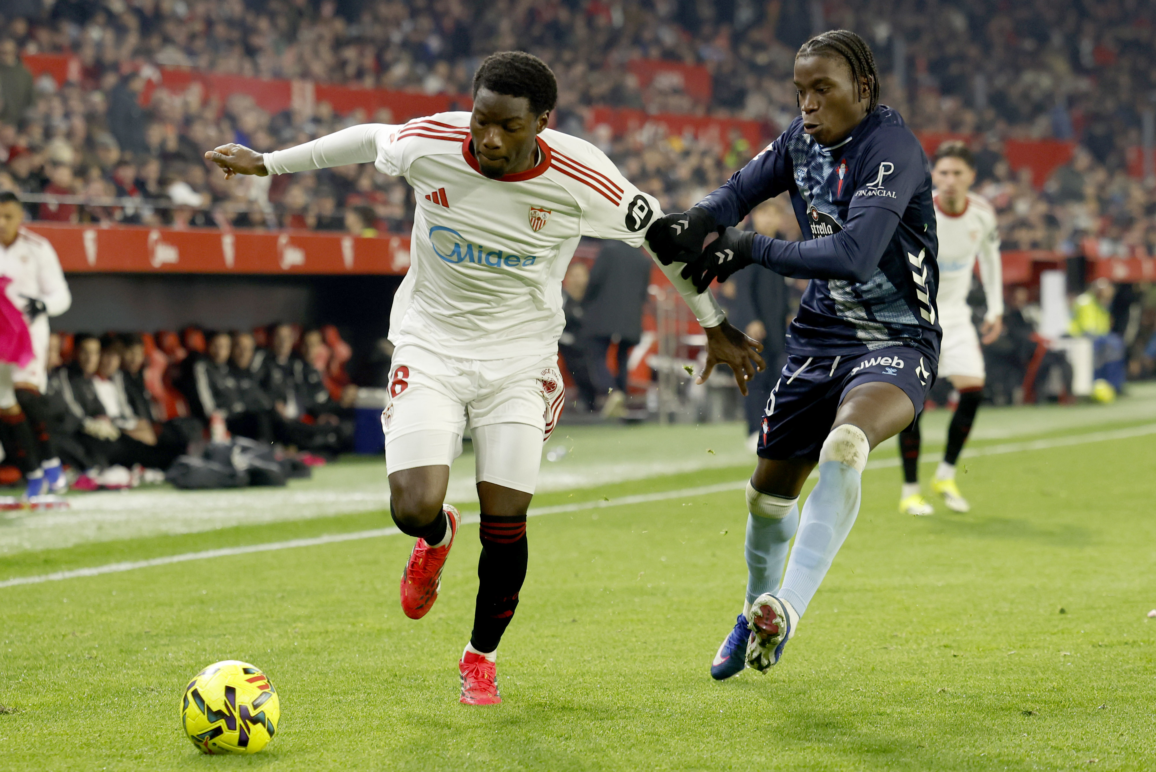 SEVILLA, 12/01/2026.- El centrocampista francés del Sevilla, Lucien Agoumé (i), disputa el balón ante el centrocampista del Celta, Ilaix Moriba, durante el encuentro correspondiente a la jornada 19 de Laliga EA Sports que disputan hoy lunes Sevilla y Celta en el estadio Sánchez Pizjuán, en la capital andaluza. EFE / Julio Muñoz.
