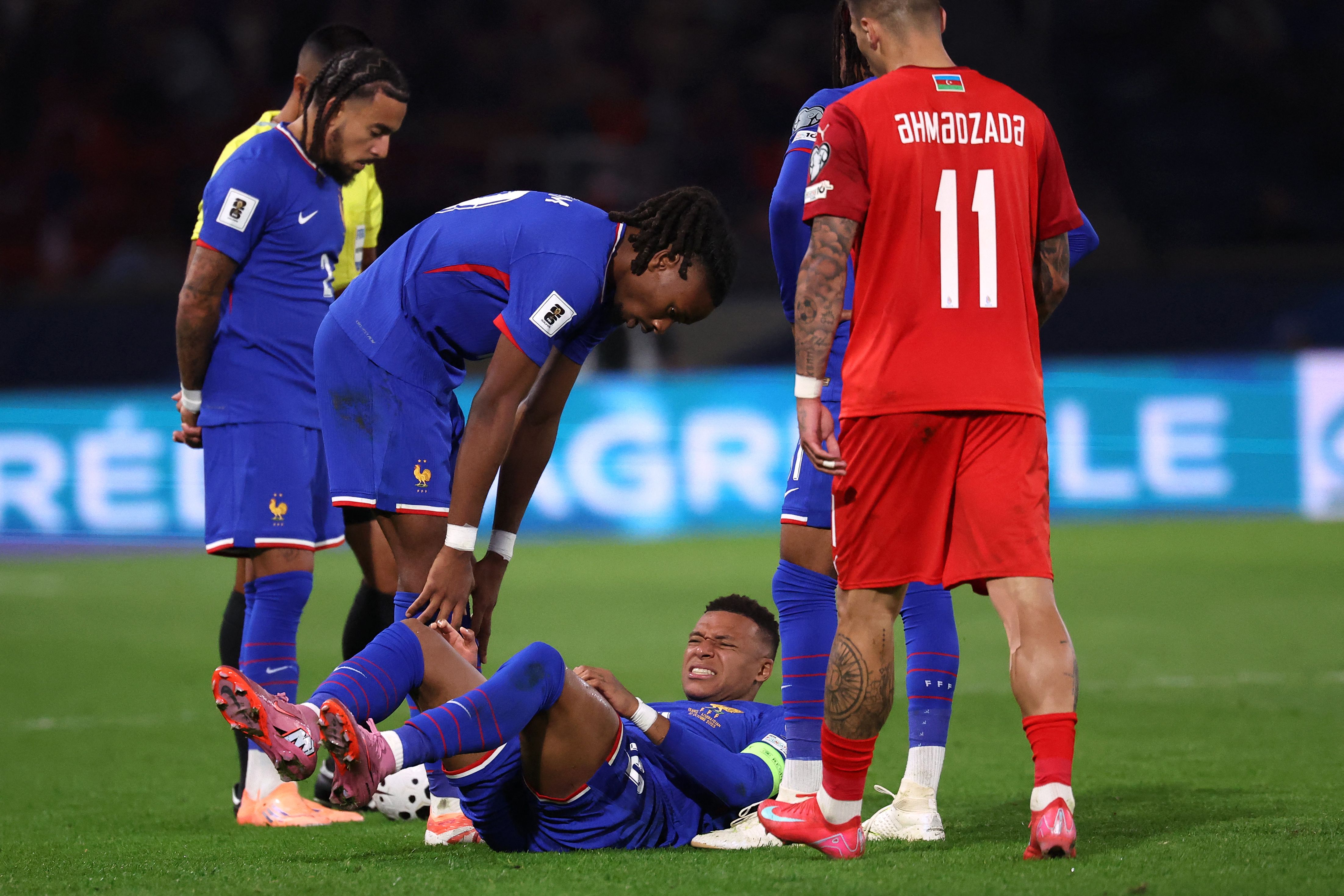 France's midfielder #19 Khephren Thuram-Ulien (2L) stands over France's forward #10 Kylian Mbappe (C) as he lies on the pitch during the FIFA World Cup 2026 Group D European qualification football match between France and Azerbaidjan at the Parc des Princes Stadium in Paris, on October 10, 2025. (Photo by Anne-Christine POUJOULAT / AFP)
