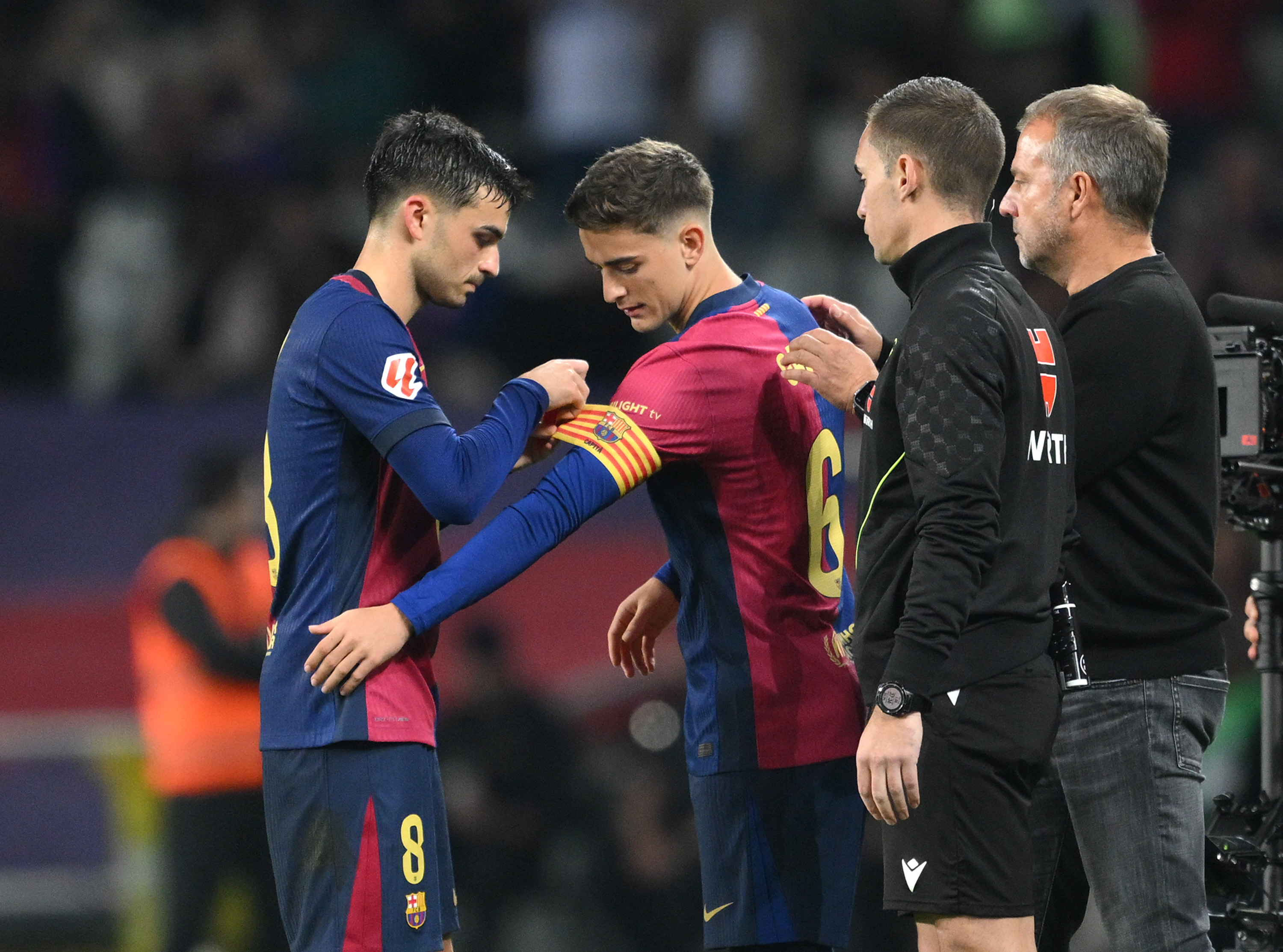 BARCELONA, SPAIN - OCTOBER 20: Pedri of FC Barcelona attaches the captain's armband onto the arm of teammate Gavi whilst being substituted during the La Liga EA Sports match between FC Barcelona and Sevilla FC at Estadi Olimpic Lluis Companys on October 20, 2024 in Barcelona, Spain. (Photo by David Ramos/Getty Images)