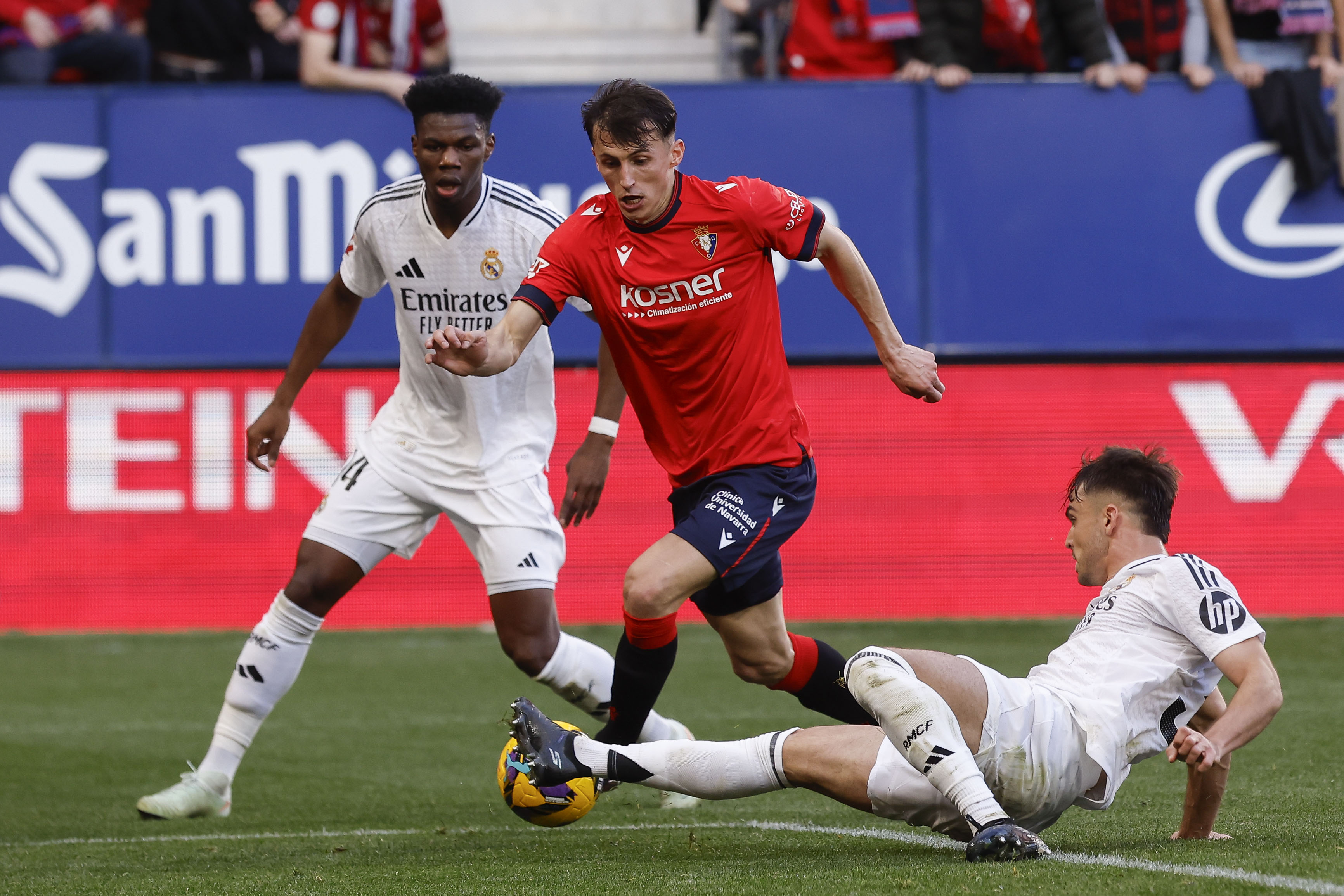 PAMPLONA, 15/02/2025.- El delantero de Osasuna Ante Budimir (c) disputa el baalón con Aurélien Tchouameni (i) y Raúl Asencio (d), del Real Madrid, Carlo Ancelotti, durante el partido de la jornada 24 de la LaLiga EA Sports, disputado este sábado en el estadio el Sadar de Pamplona. EFE/Villar López