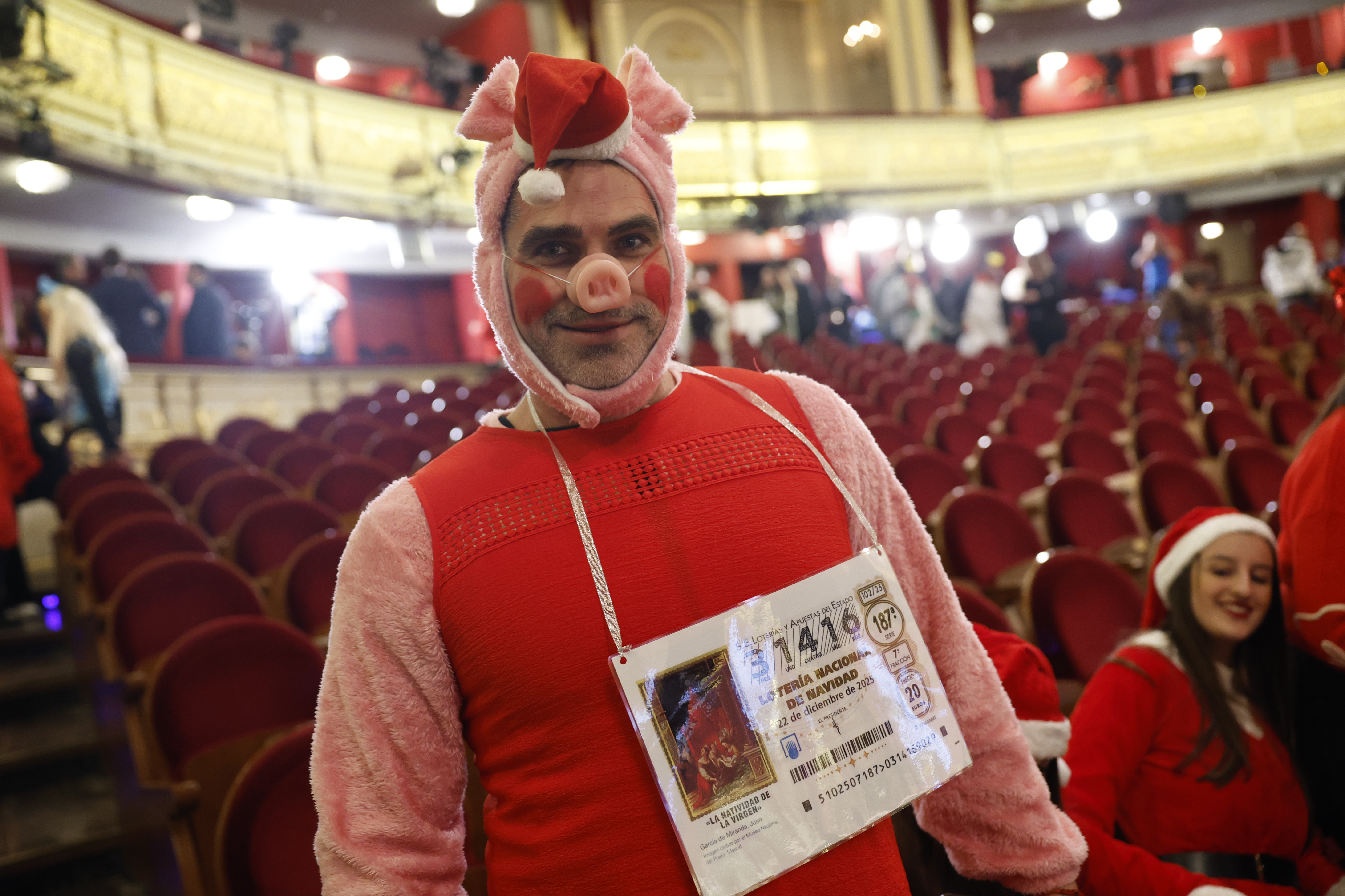Un hombre disfrazado de cerdo espera el inicio del sorteo de la Lotería de Navidad 2025 en el Teatro Real.