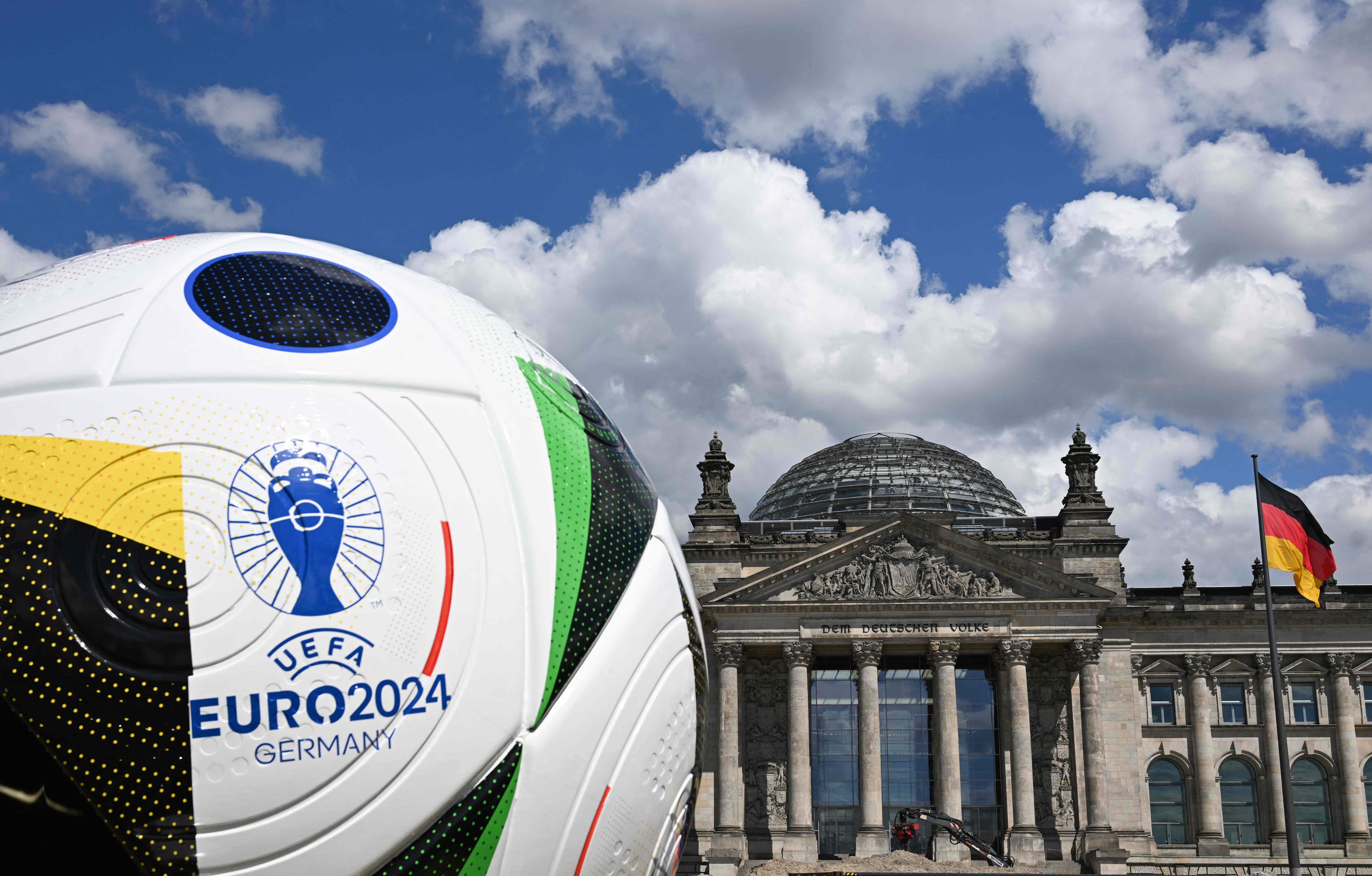 A giant ball of the upcoming UEFA Euro 2024 European Football Championship stands in front of the Reichstag building that houses the Bundestag (lower house of parliament) on June 13, 2024. (Photo by RALF HIRSCHBERGER / AFP)