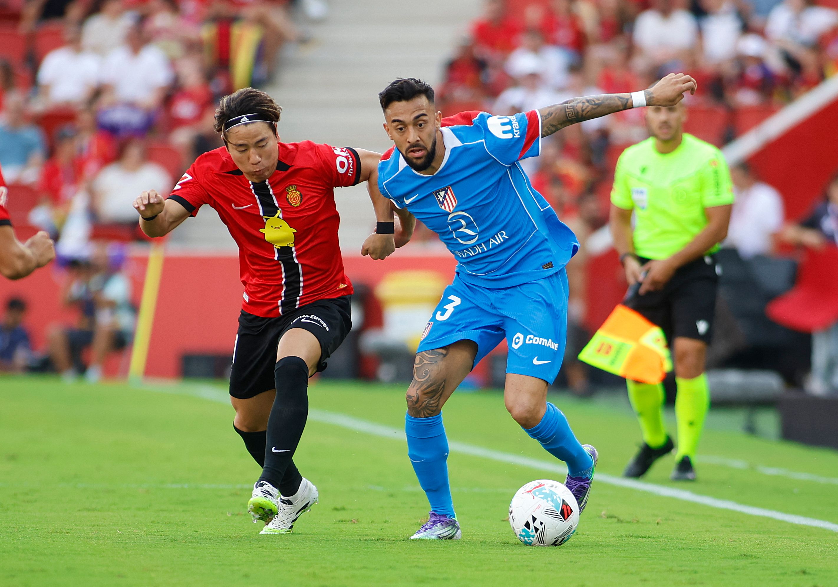 Atletico Madrid's Argentinian forward #23 Nico Gonzalez (R) vies with Real Mallorca�s Japanese forward #11 Takuma Asano during the Spanish League football match between Real Mallorca and Atletico Madrid's at the Son Moix stadium in Palma de Mallorca on September 21, 2025. (Photo by JAIME REINA / AFP)