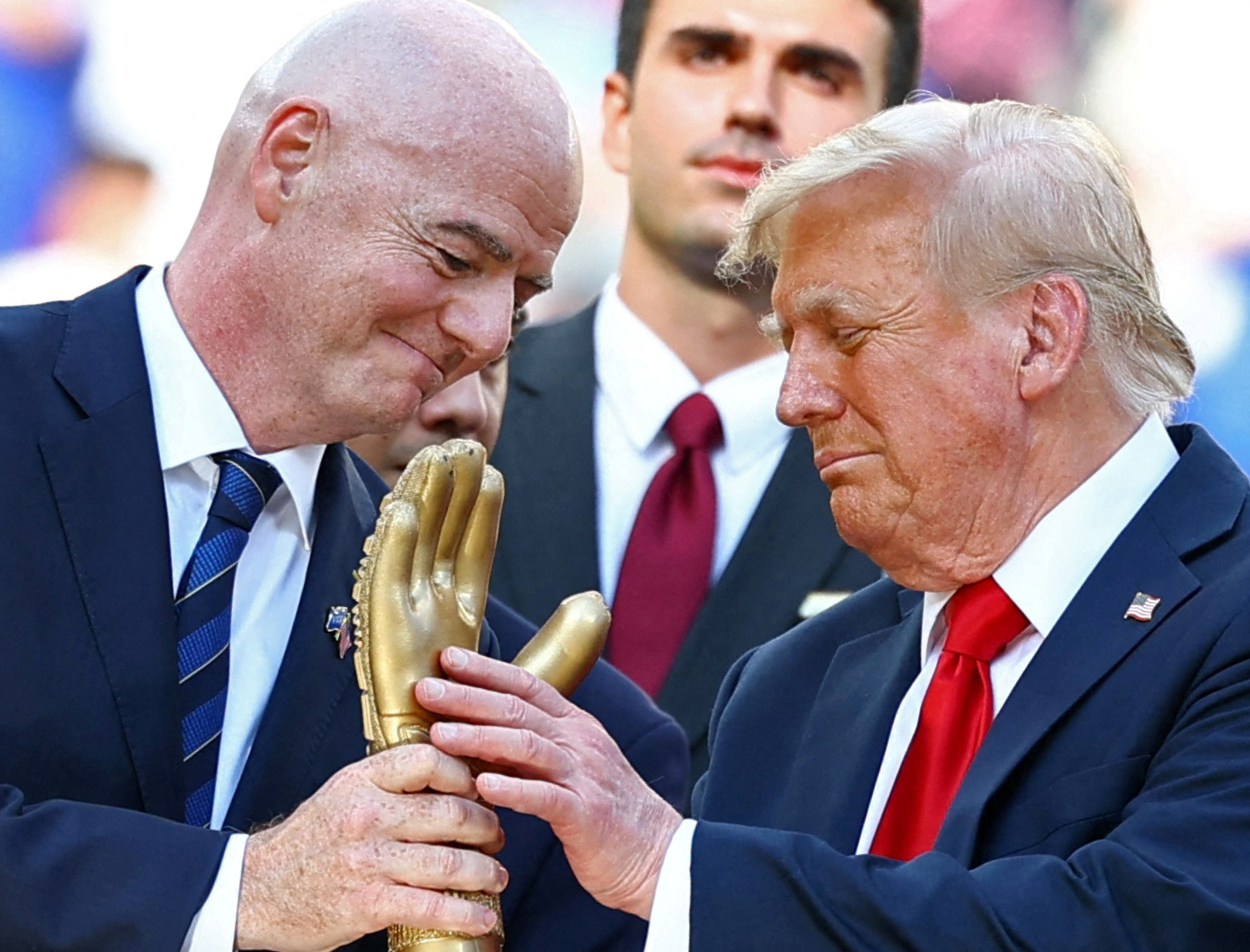 U.S. President Donald Trump looks at the golden glove trophy next to FIFA president Gianni Infantino after Chelsea won against Paris St Germain in the FIFA Club World Cup final, at the MetLife Stadium in East Rutherford, New Jersey, U.S., July 13, 2025.  REUTERS/Kai Pfaffenbach