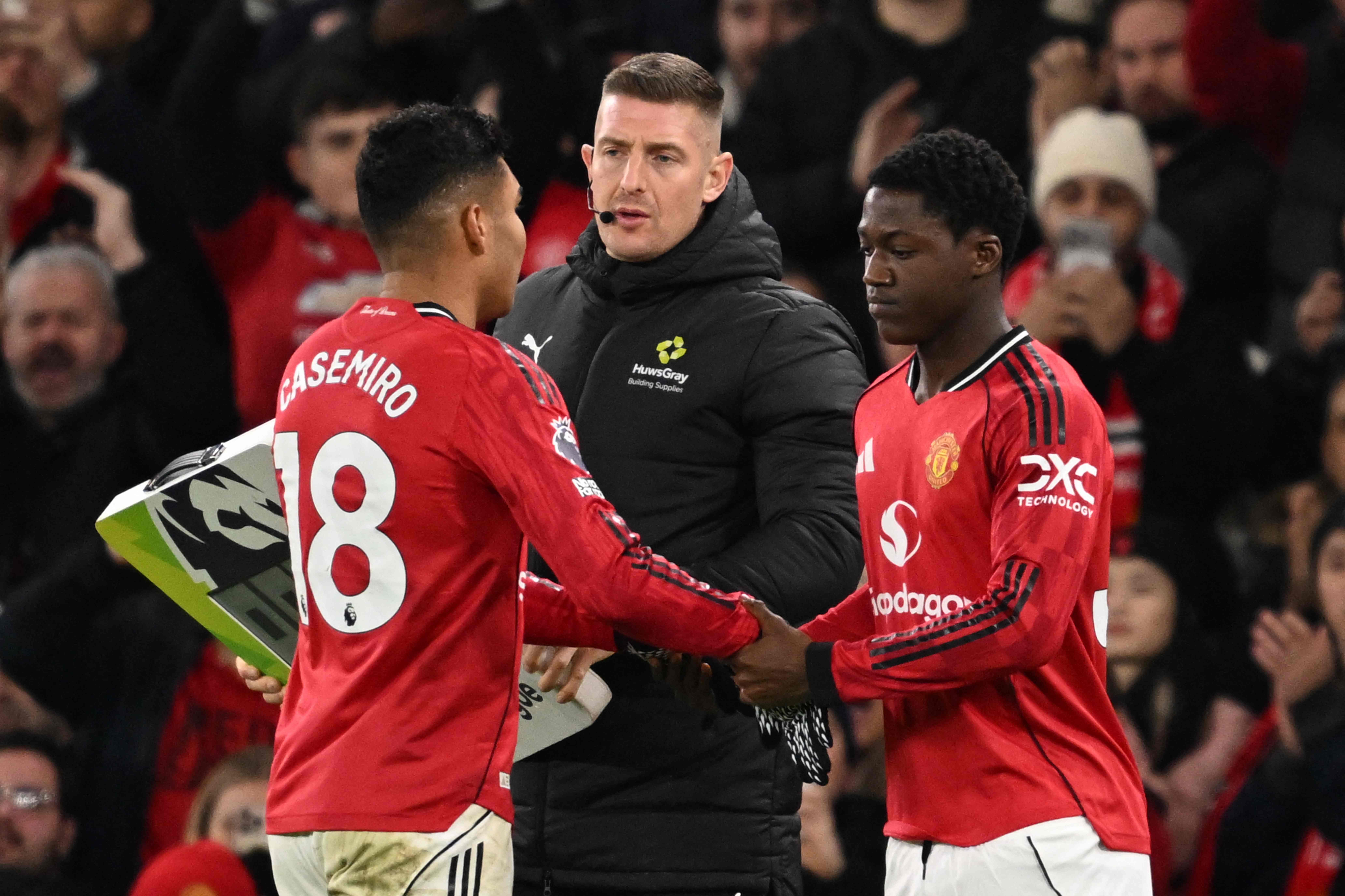 Manchester United's Brazilian midfielder #18 Casemiro (L) goes off to be replaced by Manchester United's English midfielder #37 Kobbie Mainoo (R) reacts during the English Premier League football match between Manchester United and Bournemouth at Old Trafford in Manchester, north west England, on December 15, 2025. (Photo by PETER POWELL / AFP) / RESTRICTED TO EDITORIAL USE. No use with unauthorized audio, video, data, fixture lists, club/league logos or 'live' services. Online in-match use limited to 120 images. An additional 40 images may be used in extra time. No video emulation. Social media in-match use limited to 120 images. An additional 40 images may be used in extra time. No use in betting publications, games or single club/league/player publications. / 