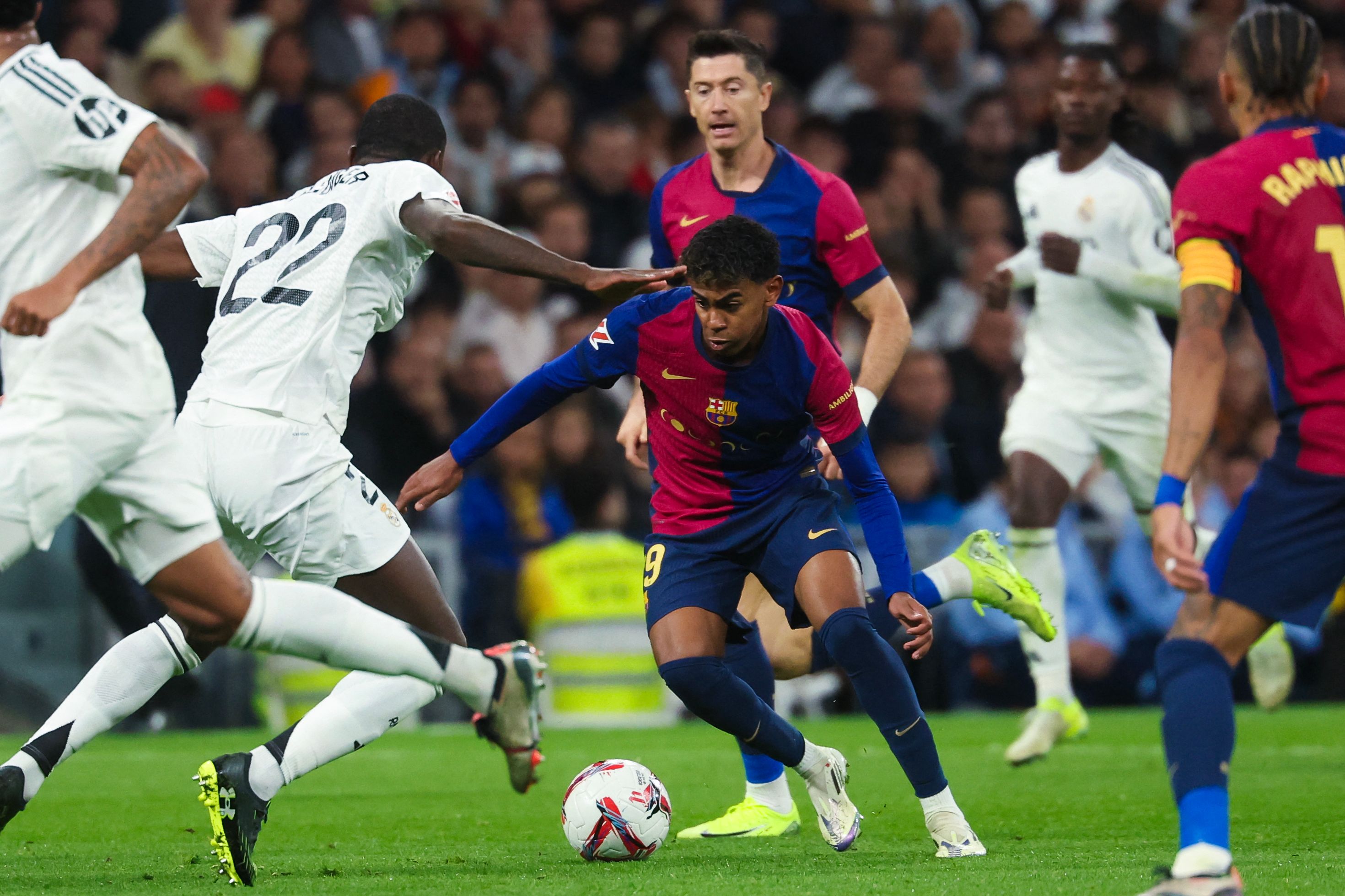 Barcelona's Spanish forward #19 Lamine Yamal (C) is challenged by Real Madrid's German defender #22 Antonio Ruediger during the Spanish league football match between Real Madrid CF and FC Barcelona at the Santiago Bernabeu stadium in Madrid on October 26, 2024. (Photo by Pierre-Philippe MARCOU / AFP)