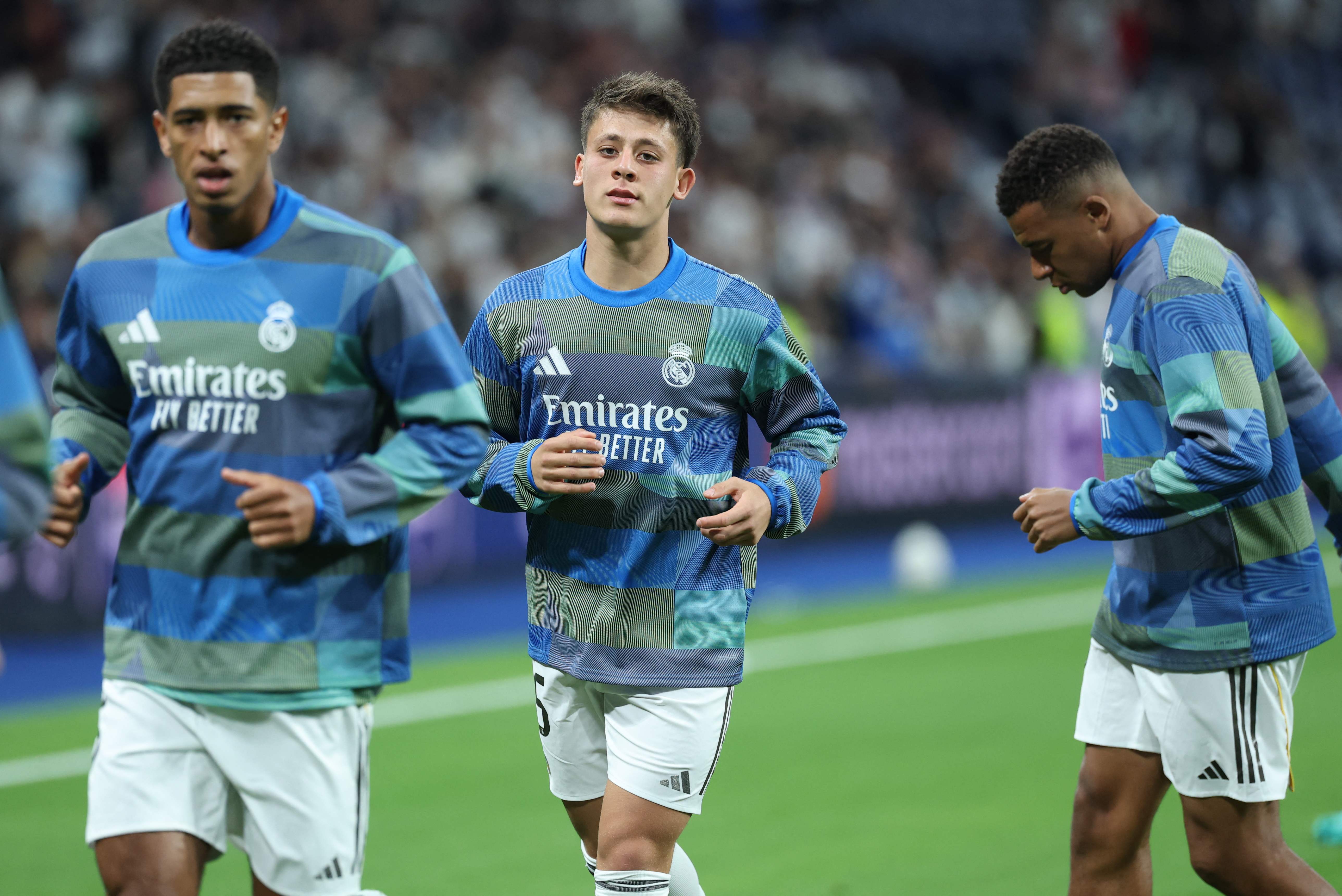 Real Madrid's English midfielder #05 Jude Bellingham (L) Real Madrid's Turkish midfielder #15 Arda Guler and Real Madrid's French forward #10 Kylian Mbappe (R) warm up before the UEFA Champions League league phase day 3 football match between Real Madrid CF and Juventus at Santiago Bernabeu Stadium in Madrid on October 22, 2025. (Photo by Thomas COEX / AFP)