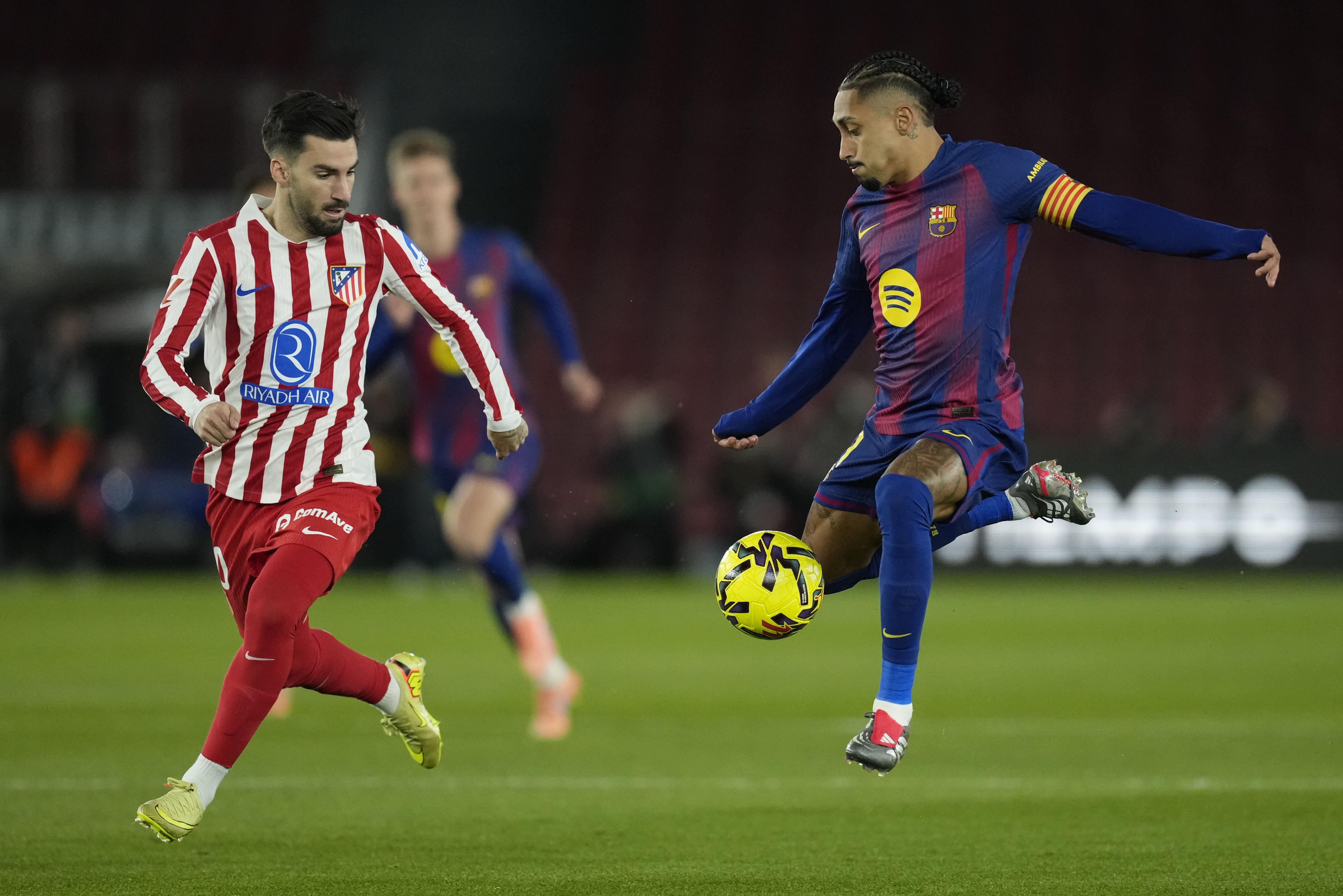 BARCELONA, 02/12/2025.- El delantero del FC Barcelona Raphinha (d), en acción ante el centrocampista del Atlético de Madrid Alex Baena (i) durante el partido adelantado de la jornada 19 de Liga disputado en el Camp Nou de Barcelona. EFE/Enric Fontcuberta