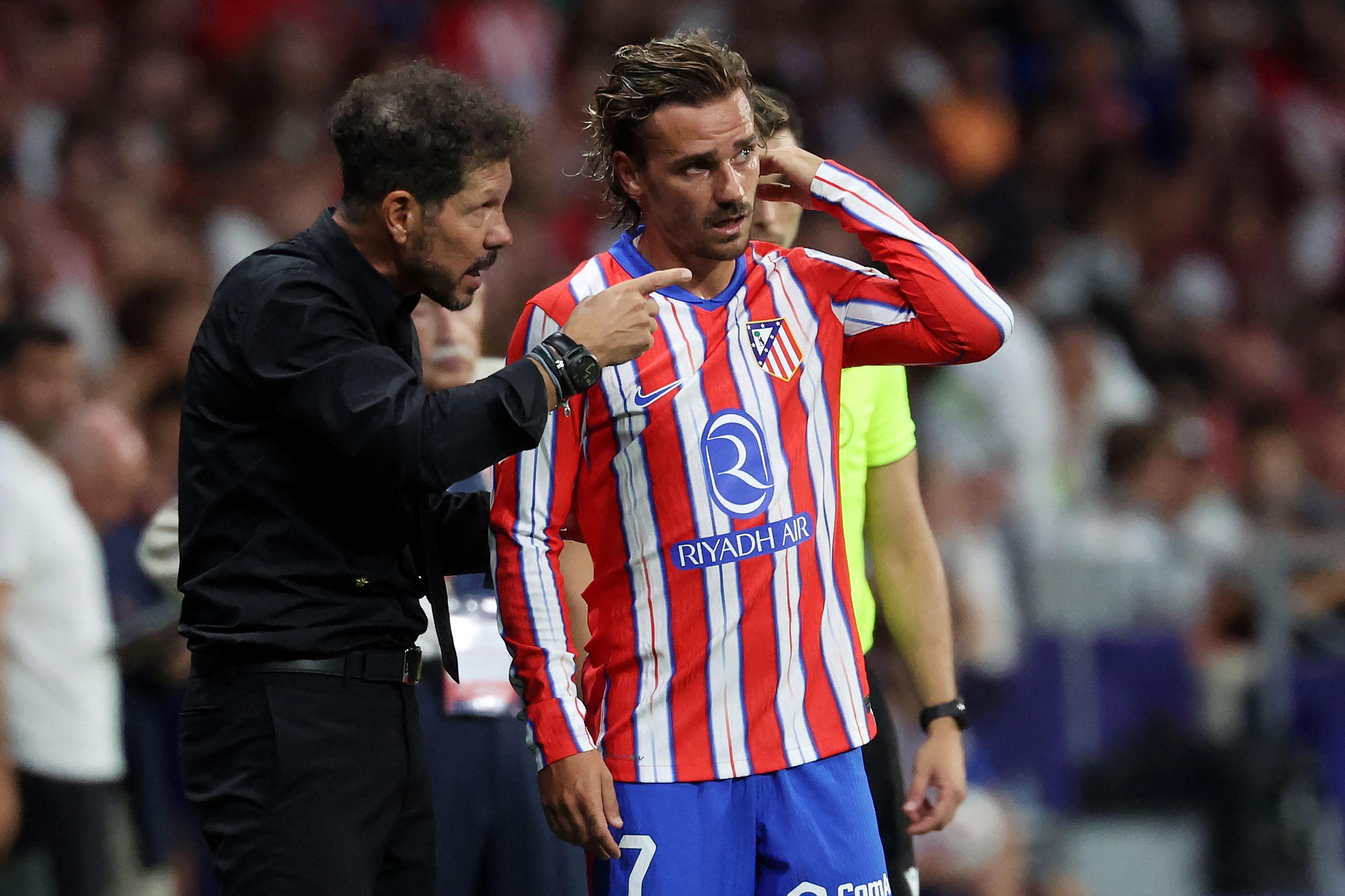 Atletico Madrid's Argentine coach Diego Simeone (L) speaks to Atletico Madrid's French forward #07 Antoine Griezmann during the Spanish league football match between Club Atletico de Madrid and Girona FC at the Metropolitano stadium in Madrid on August 25, 2024. (Photo by Pierre-Philippe MARCOU / AFP)