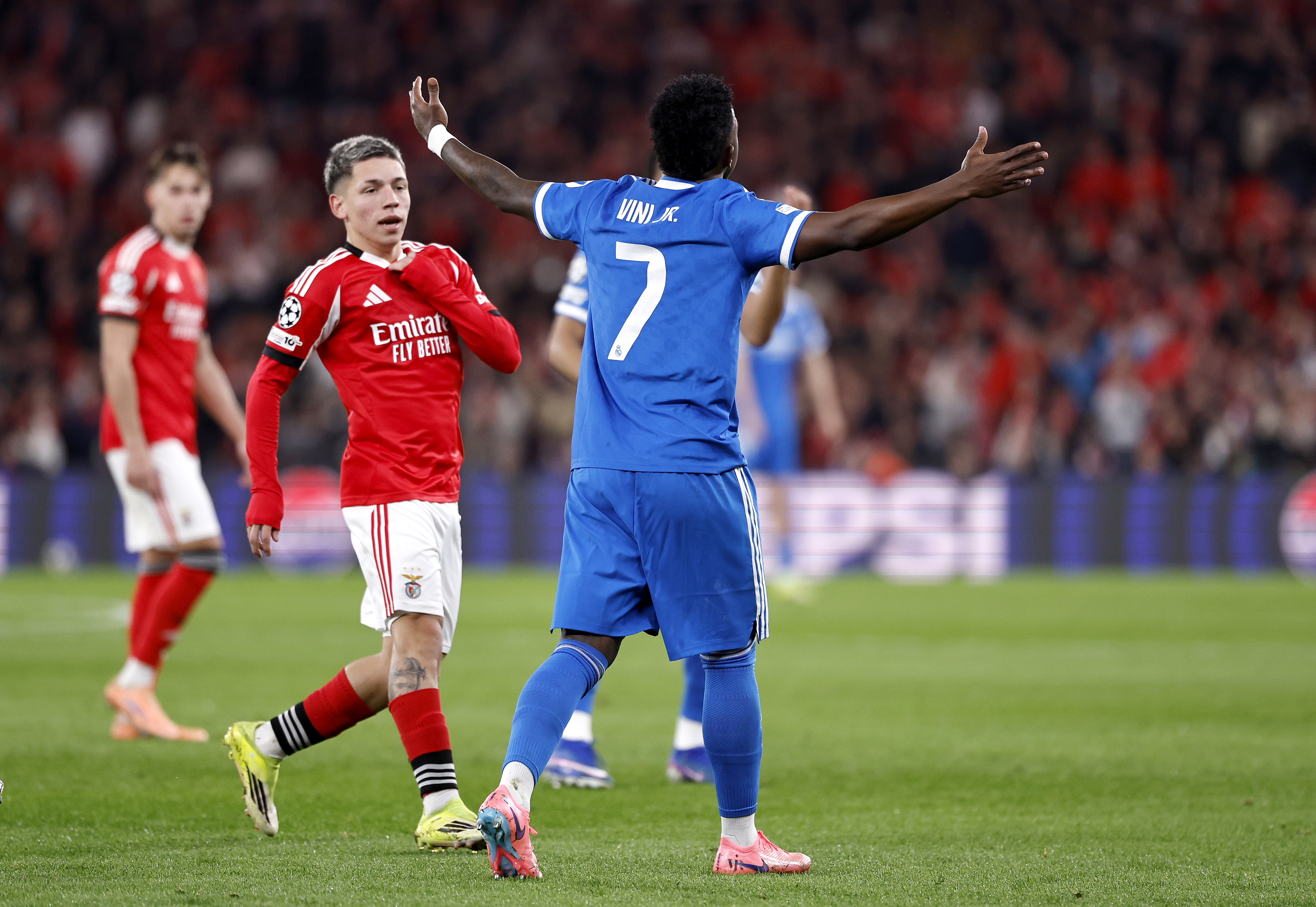El jugador argentino del Benfica se tapa la boca con la camiseta y algo le dice a Vinicius.