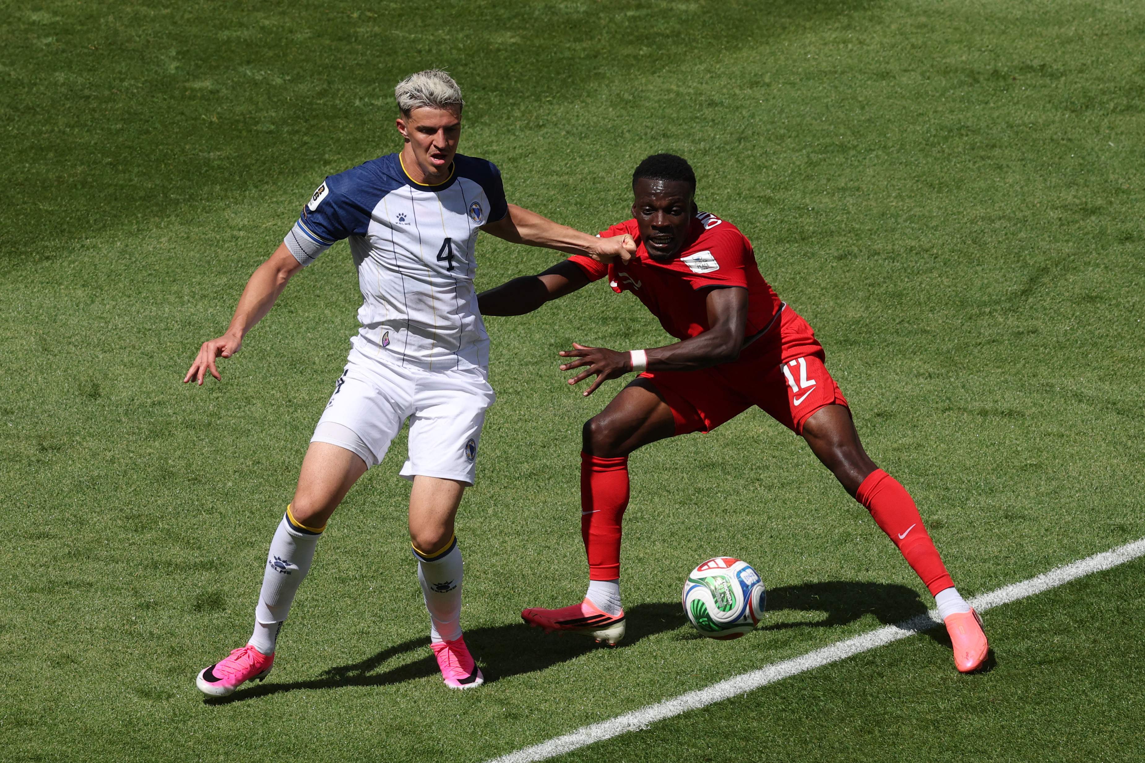 TORONTO, ONTARIO - JUNE 12: Tarik Muharemovic #4 of Bosnia and Herzegovina competes for the ball against Tani Oluwaseyi #12 of Canada during the FIFA World Cup 2026 Group B match between Canada and Bosnia and Herzegovina at Toronto Stadium on June 12, 2026 in Toronto, Ontario.   Michael Steele/Getty Images/AFP (Photo by MICHAEL STEELE / GETTY IMAGES NORTH AMERICA / Getty Images via AFP)