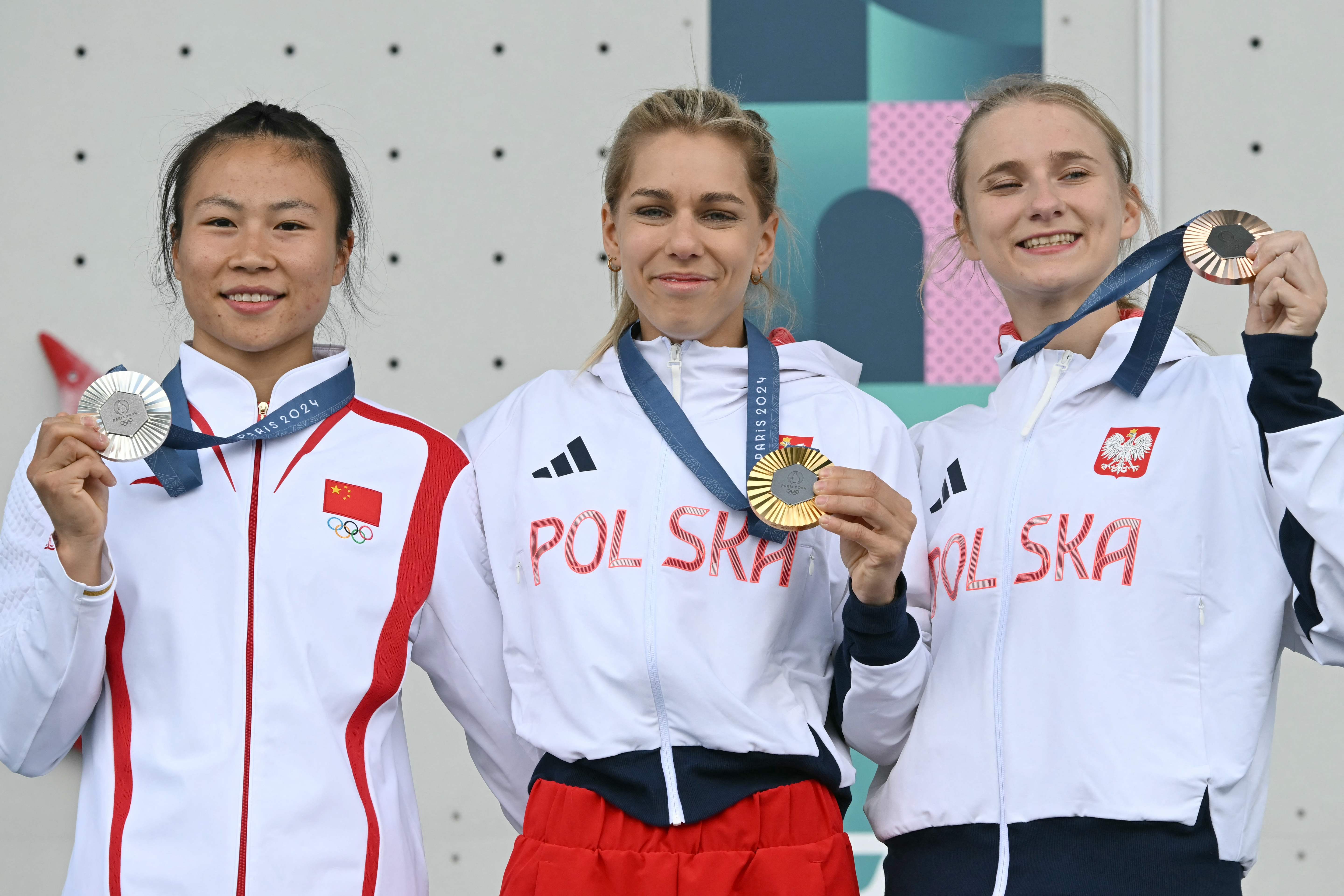 Silver medallist China's Deng Lijuan (L), gold medallist Poland's Aleksandra Miroslaw and bronze medallist Poland's Aleksandra Kalucka celebrate on the podium during the medal ceremony for the the women's sport climbing speed competition during the Paris 2024 Olympic Games at Le Bourget Sport Climbing Venue in Le Bourget on August 7, 2024. (Photo by Fabrice COFFRINI / AFP)