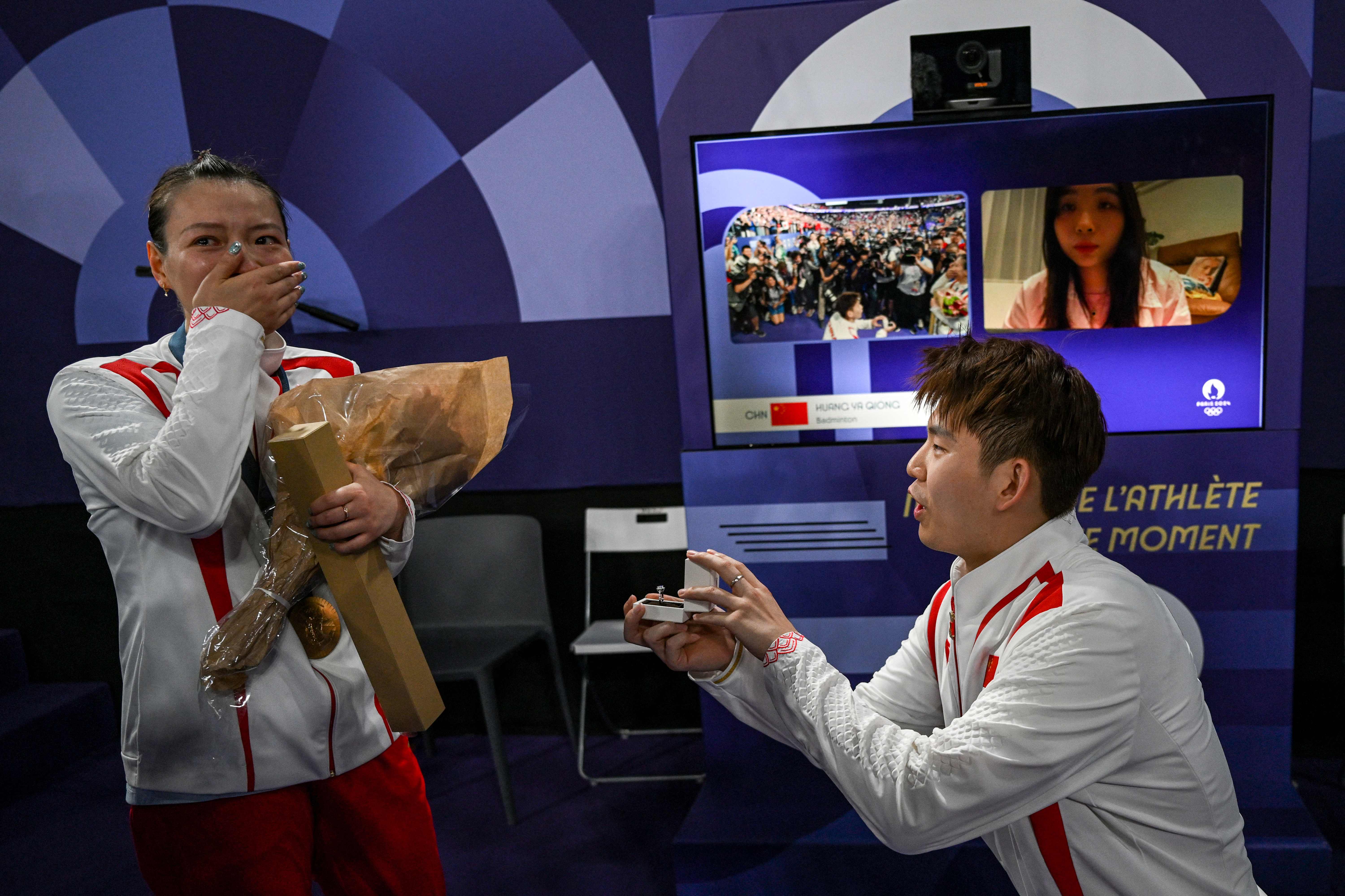 CORRECTION / China's Liu Yuchen proposes to his partner and gold medallist Huang Ya Qiong after leaving the podium at the mixed doubles badminton medal ceremony during the Paris 2024 Olympic Games at Porte de la Chapelle Arena in Paris on August 2, 2024. (Photo by ARUN SANKAR / AFP) / �The erroneous mention[s] appearing in the metadata of this photo has been modified in AFP systems in the following manner: [Correcting identity to Liu Yuchen from Zheng Siwei]. Please immediately remove the erroneous mention[s] from all your online services and delete it (them) from your servers. If you have been authorized by AFP to distribute it (them) to third parties, please ensure that the same actions are carried out by them. Failure to promptly comply with these instructions will entail liability on your part for any continued or post notification usage. Therefore we thank you very much for all your attention and prompt action. We are sorry for the inconvenience this notification may cause and remain at your disposal for any further information you may require.�