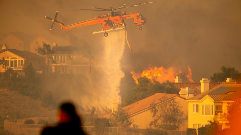 Un hélicoptère largue de l'eau pour tenter de stopper l'incendie baptisé "Saddleridge Fire" qui progresse à une vingtaine de km au nord de Los Angeles, le 11 octobre 2019.
