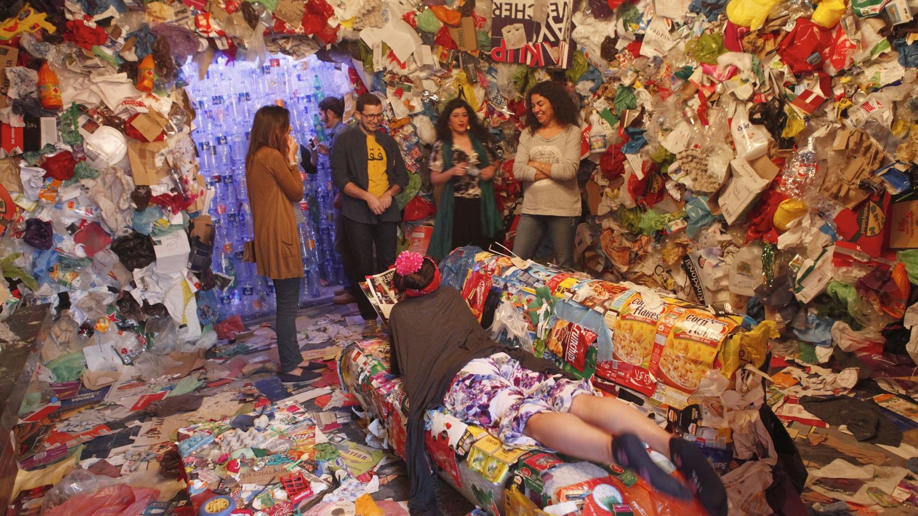 Après avoir traversé un couloir de rideaux de bouteilles usagées, les visiteurs débarquent dans une pièce dont les murs sont recouverts de déchets et de vieux objets. L'actrice Fatim El Aychi, installée dans un fauteuil, semble adorer.
