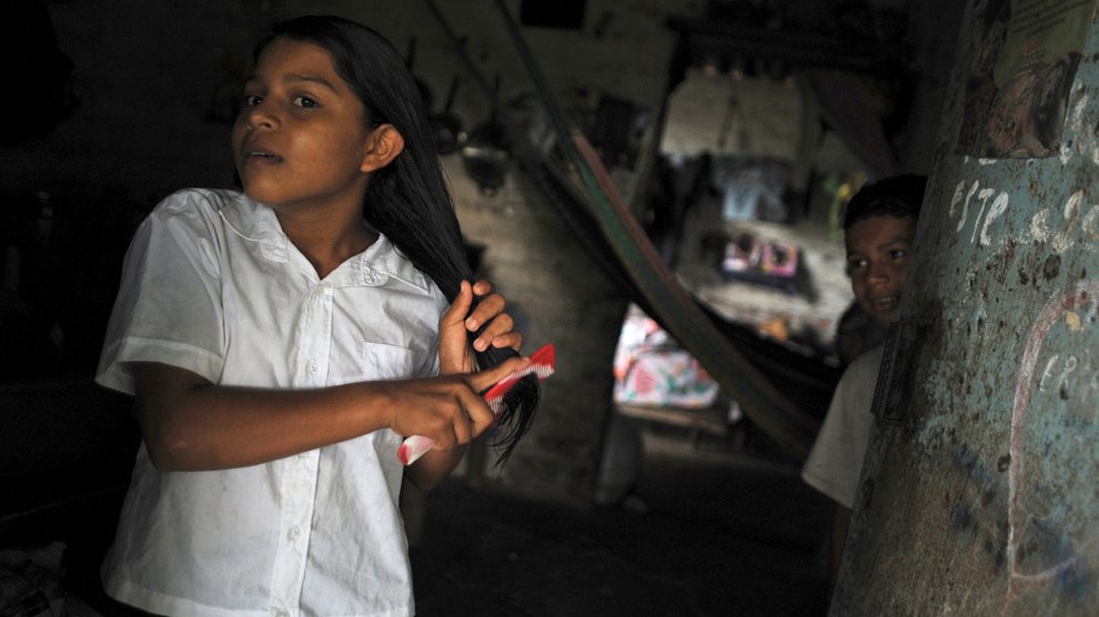 Silvia Alvarado, 10 ans, se prépare pour aller à l'école sous l'oeil de son petit frère. Acajutla, Salvador
