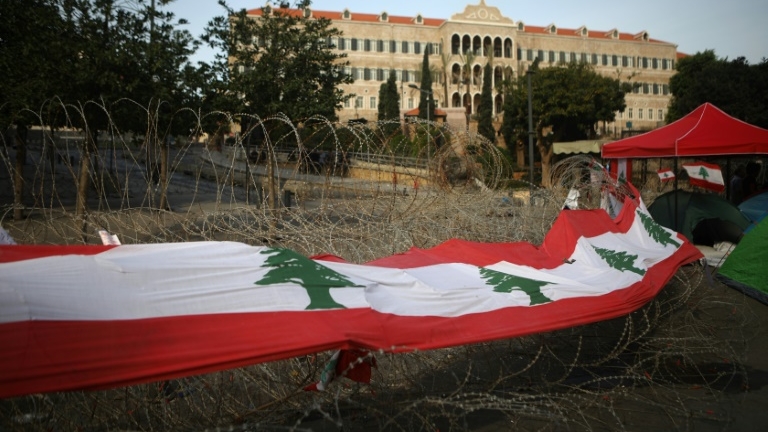 Un large drapeau libanais placé sur les barbelés devant le siège du gouvernement à Beyrouth, le 26 octobre 2019.
