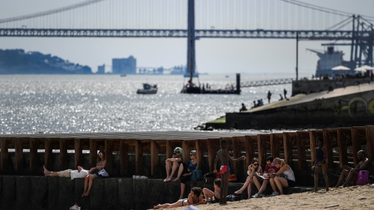 Des touristes se mettent à l'ombre sur une plage de Lisbonne, pendant un épisode de canicule, le 3 août 2018 au Portugal.
